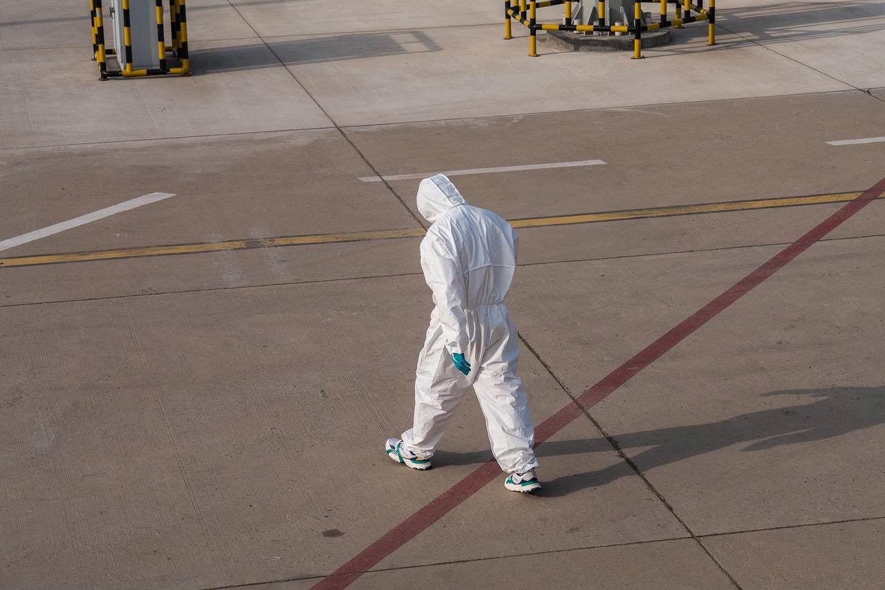 A health worker in full personal protective equipment stands ready during an outbreak response, masked and gloved for biohazard isolation duty.