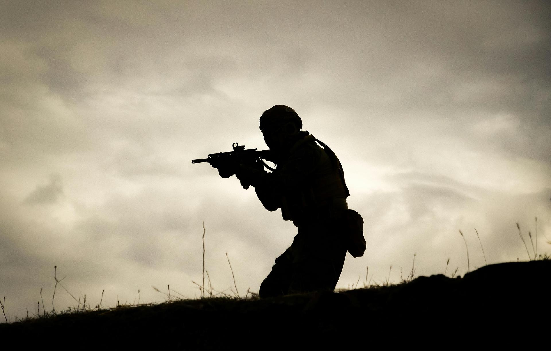 Silhouette of a lone soldier holding a rifle against a dramatic sunset sky, evoking the isolation of frontline duty.