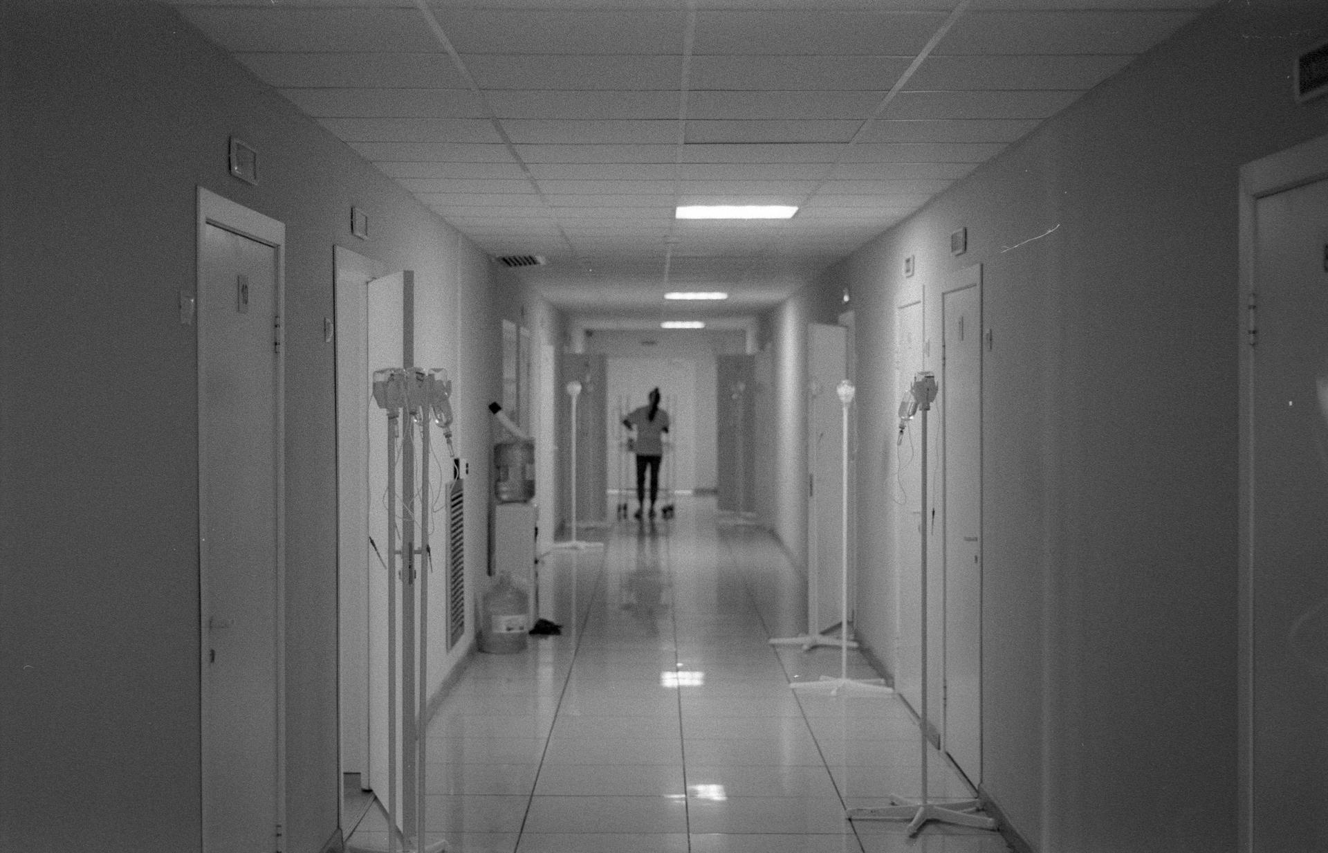 A nurse stands alone at the end of a hospital corridor, evoking the long wait Kenyan nurses face for NHS placements.
