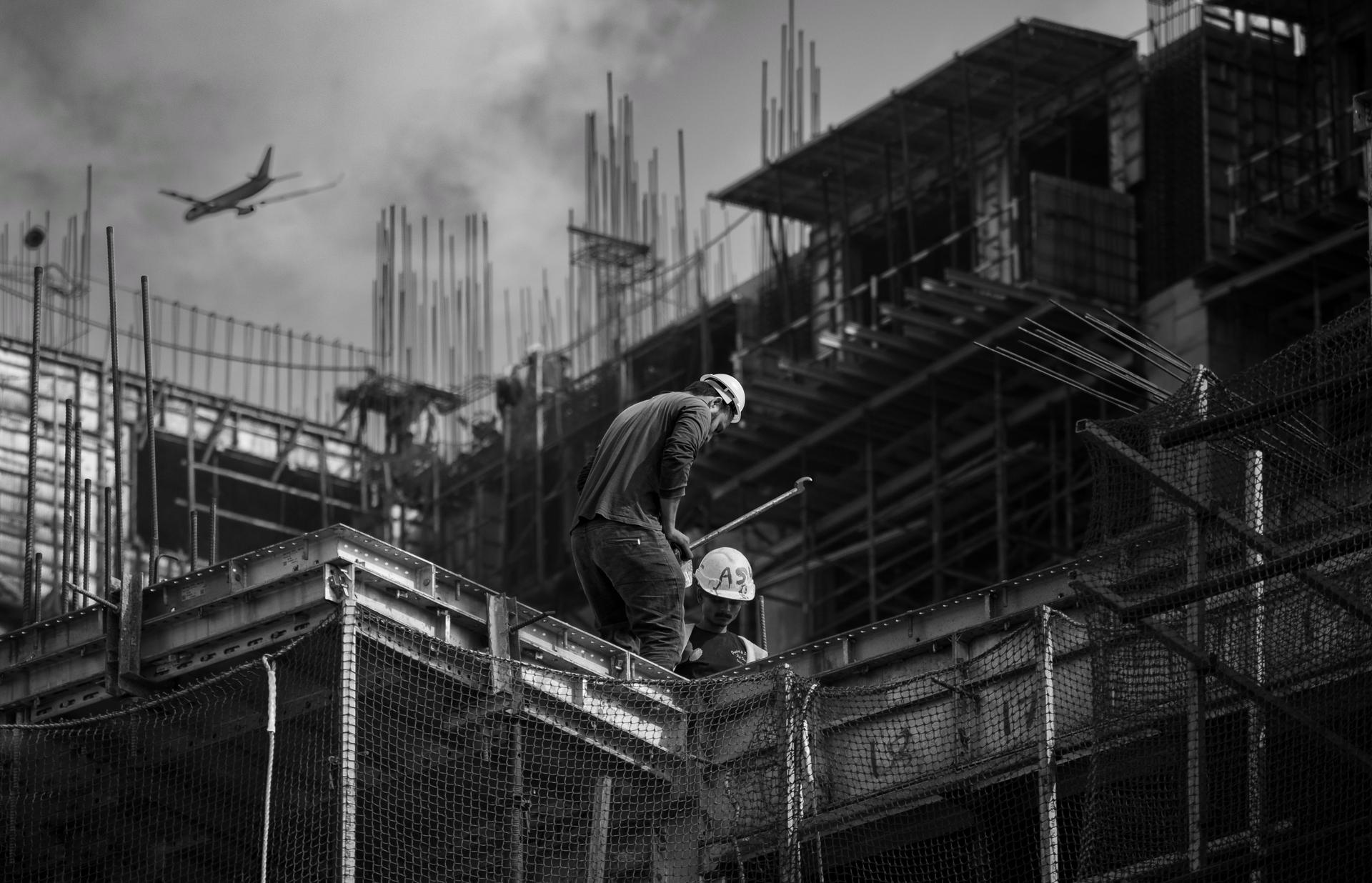 Construction workers in safety gear on the concrete and steel framework of an urban building site