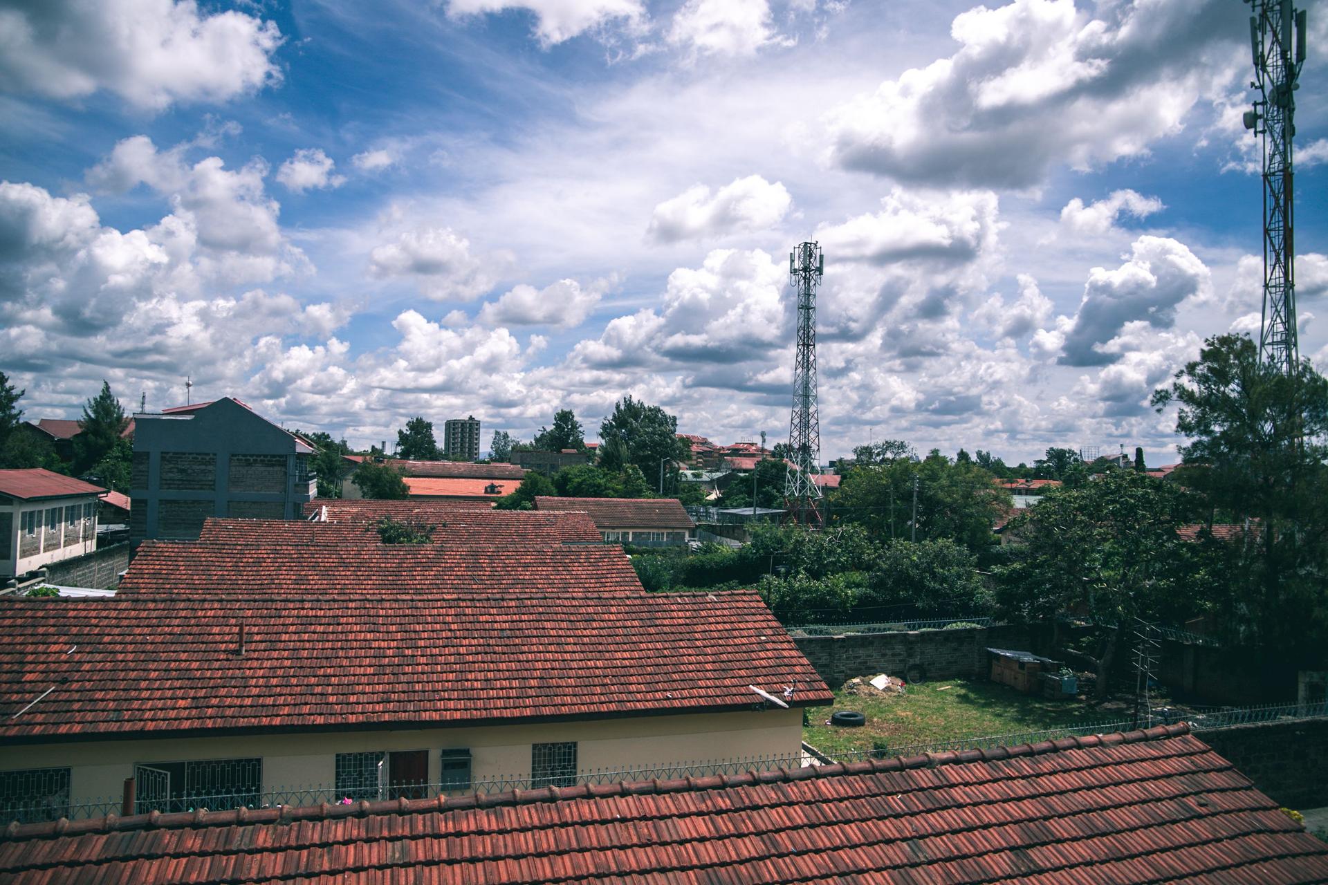 Aerial view of suburban red-tiled rooftops under a bright blue sky in a peri-urban residential area