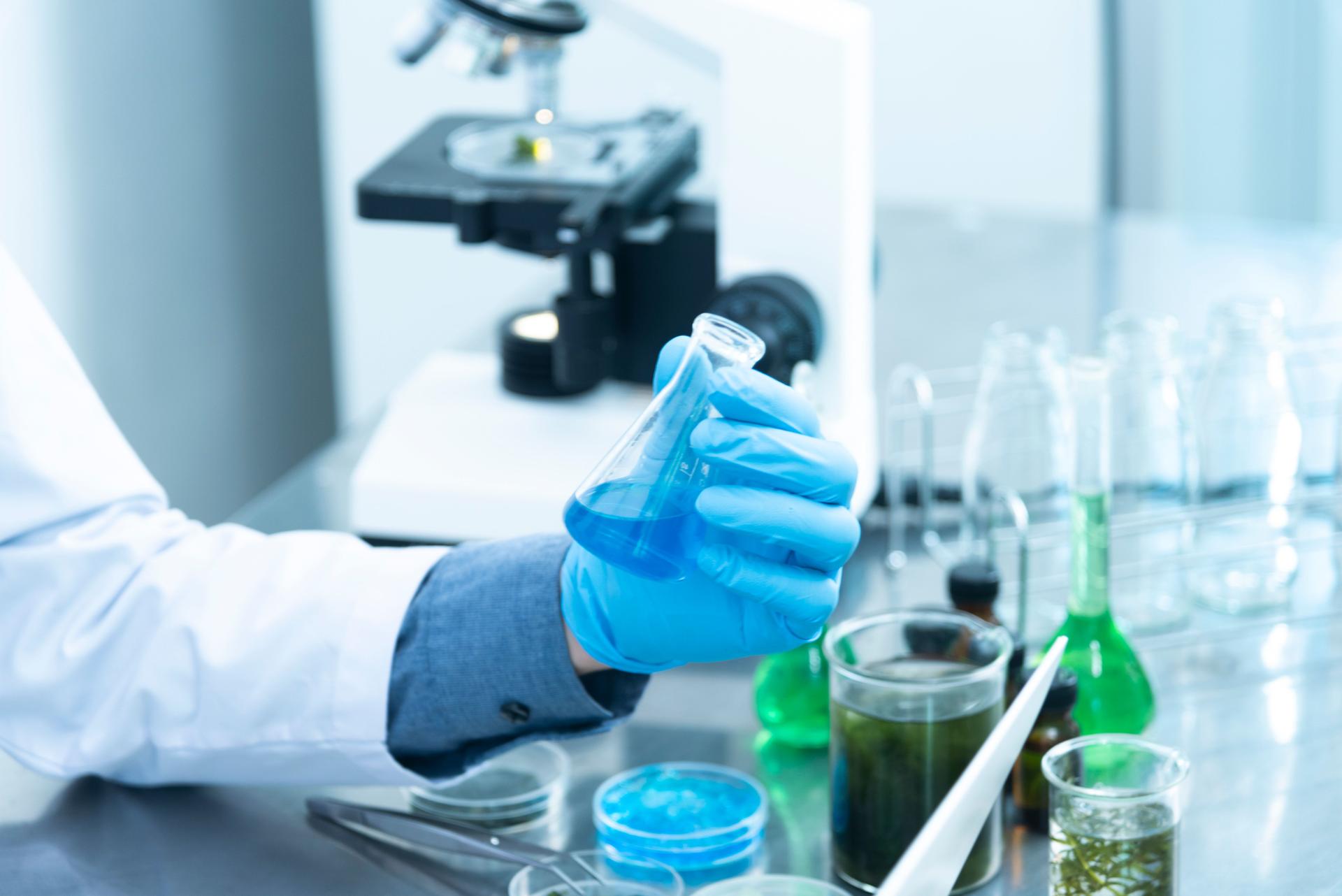 A scientist in a laboratory examines a sample under a microscope during medical research work