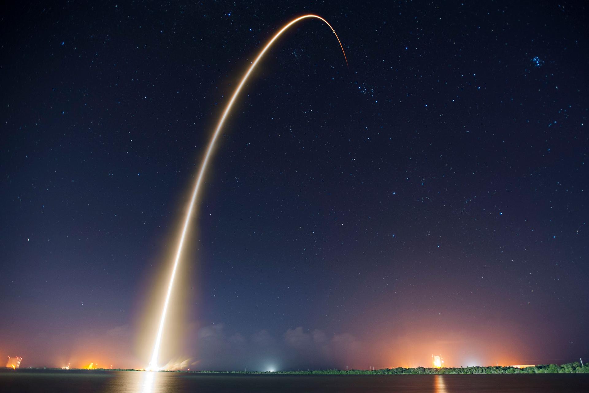 A rocket lifts off against a clear sky trailing smoke, illustrating the modern space industry.