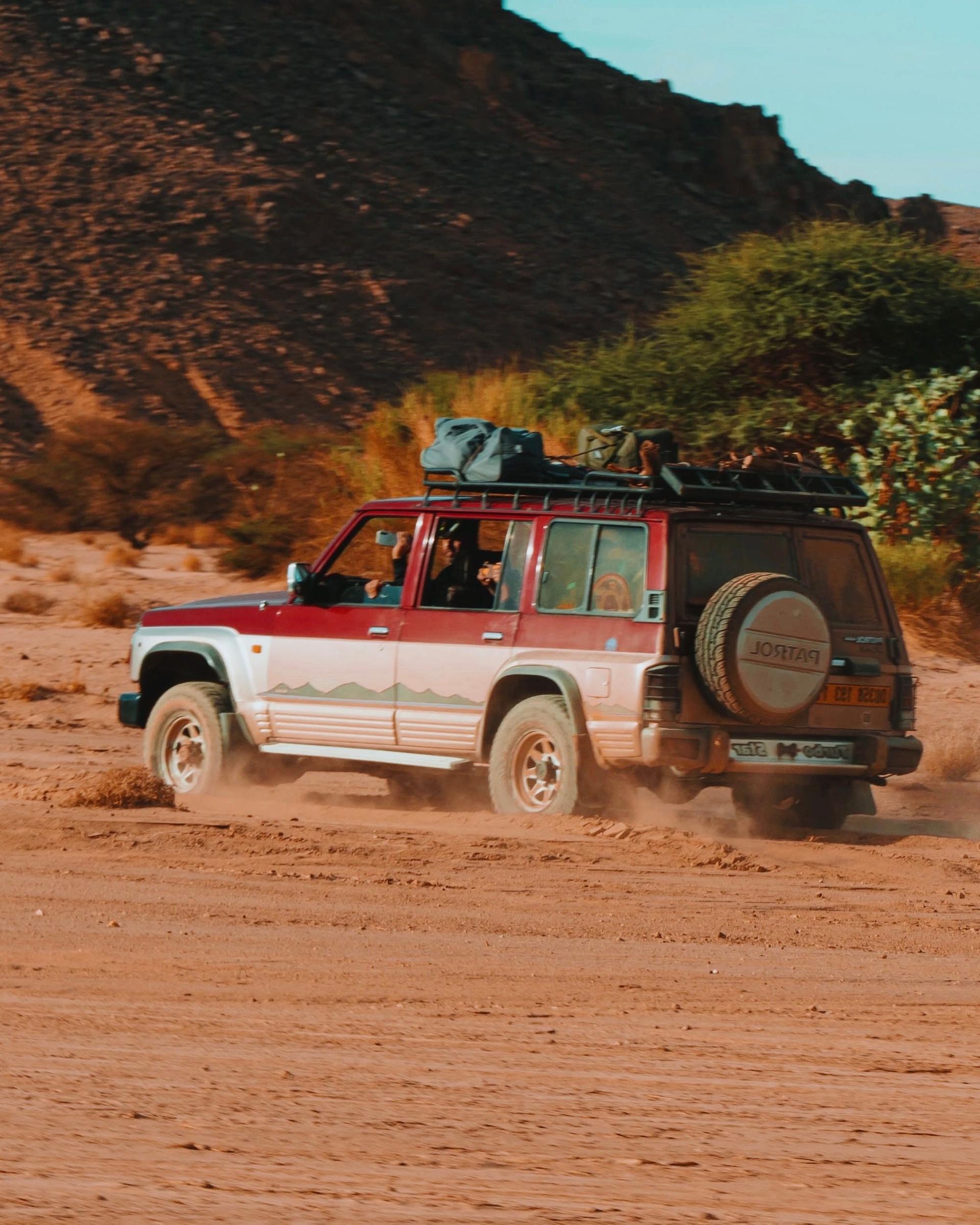 A four-wheel-drive vehicle crossing open desert terrain, evoking a long overland expedition across Africa.