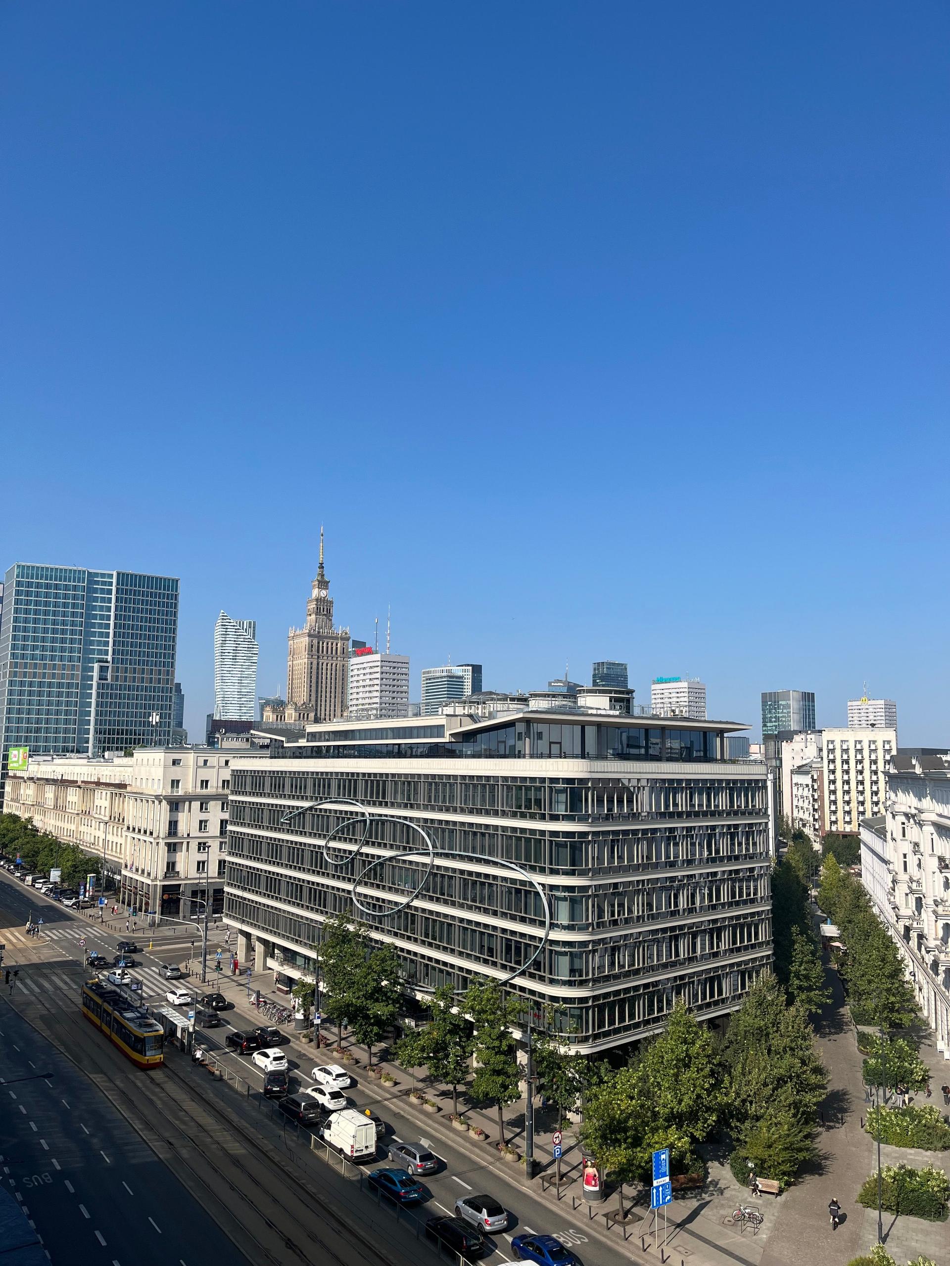 Aerial view of the Warsaw skyline with modern apartment towers and historic landmarks under a clear sky.