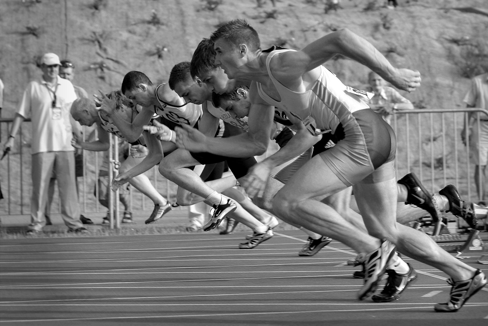 A sprinter crouches in the starting blocks on an athletics track, ready to race.
