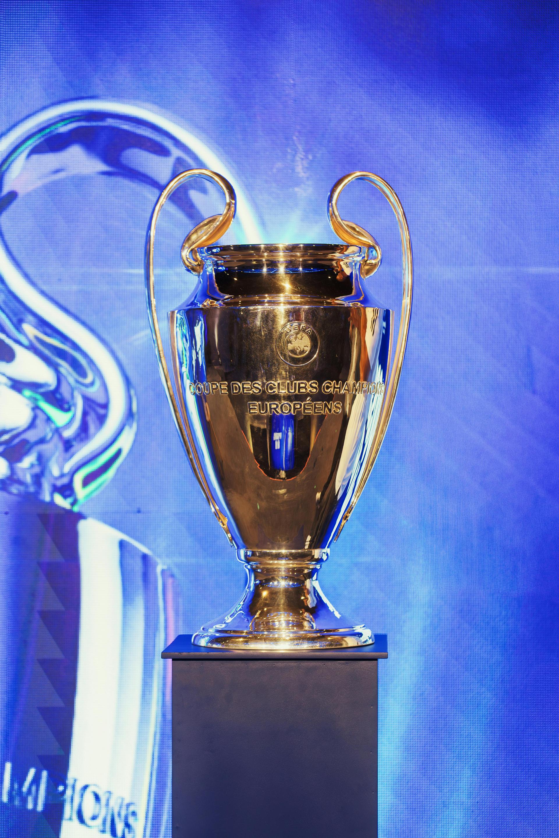 Close-up of the UEFA Champions League trophy on a pedestal under red light, the prize PSG retained against Arsenal in Saturday's final