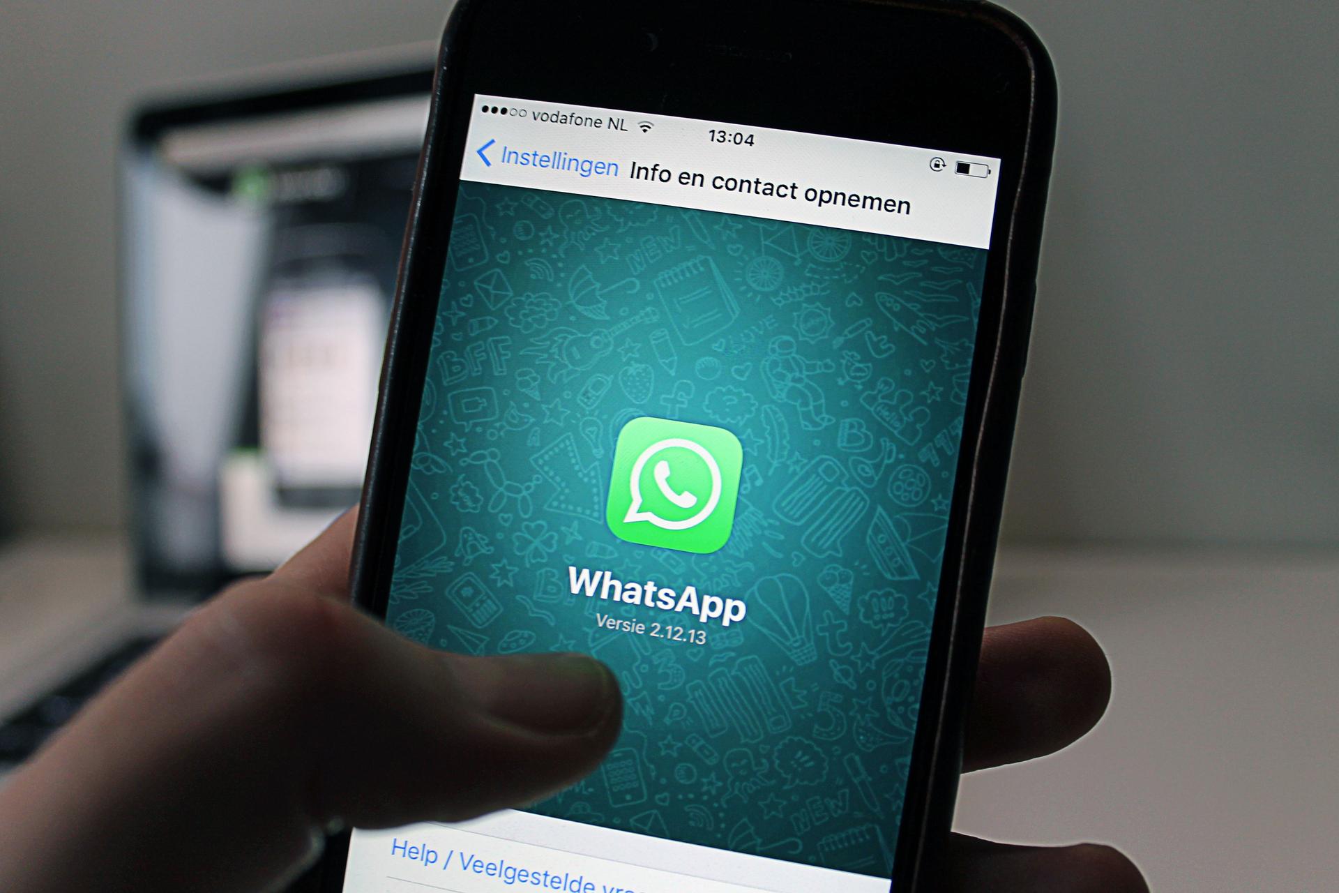A person holds a smartphone displaying the WhatsApp application screen in close-up