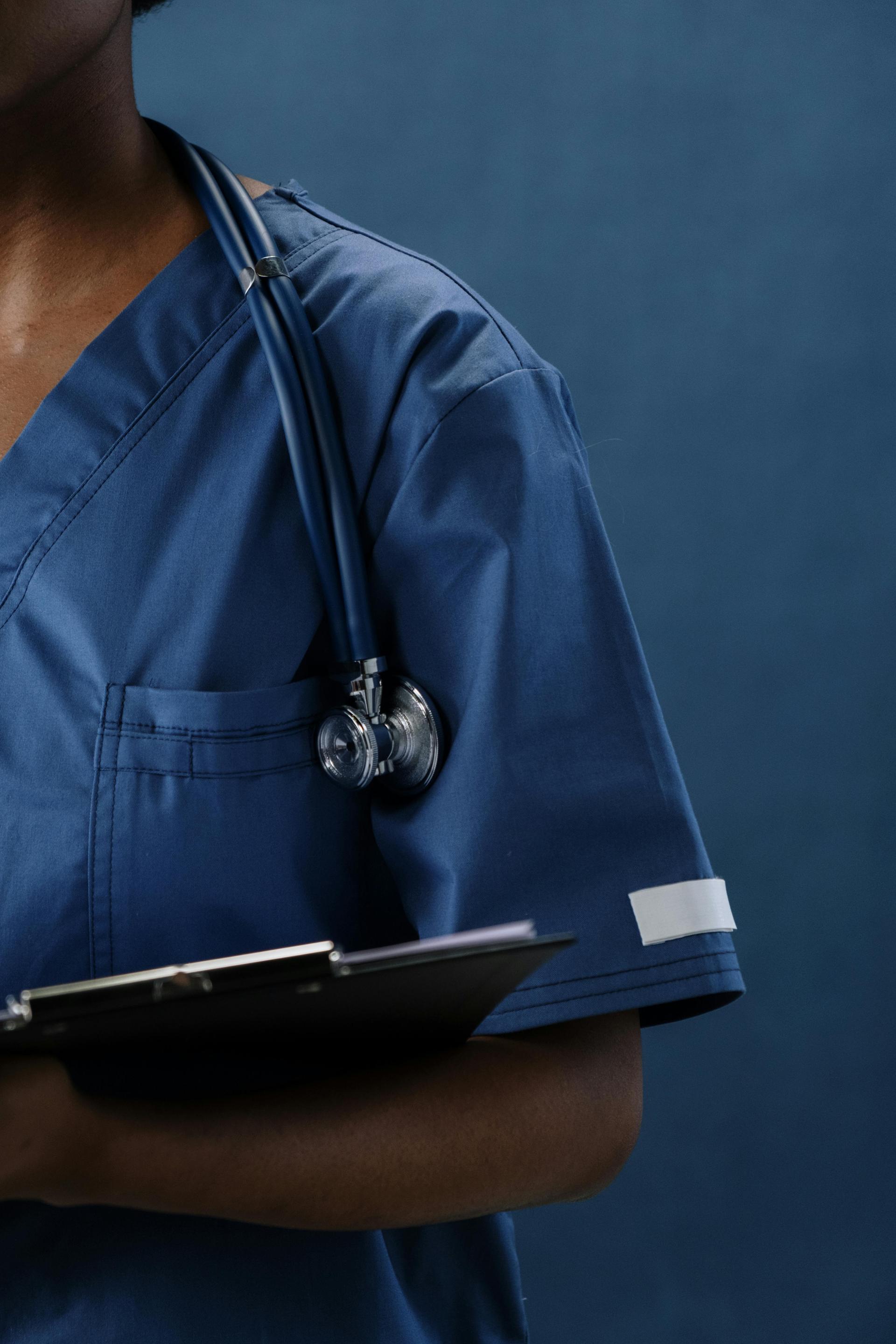 Close-up of a healthcare professional in blue scrubs with a stethoscope draped over the shoulder