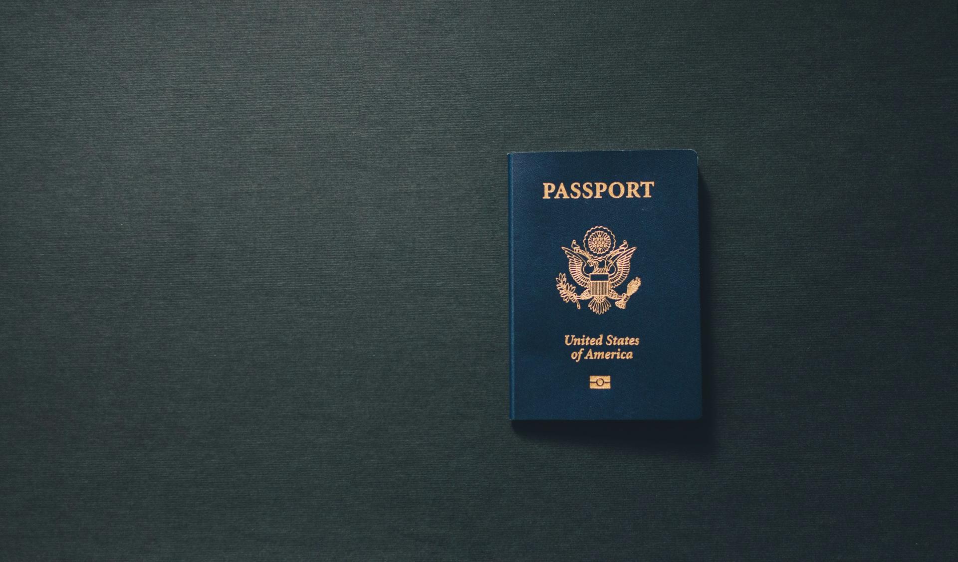 A US passport sits open on a wooden surface, illustrating an immigration-and-travel scene tied to American green-card processing.
