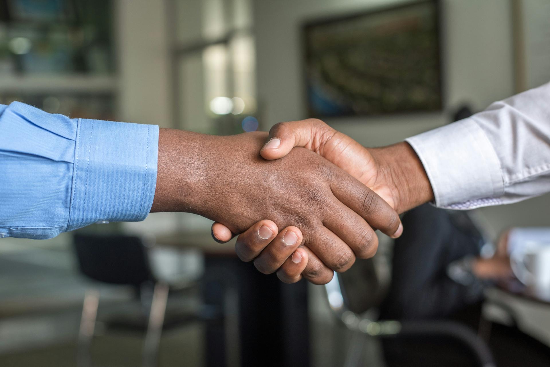Two people shaking hands across a table, symbolising a signed diplomatic cooperation agreement
