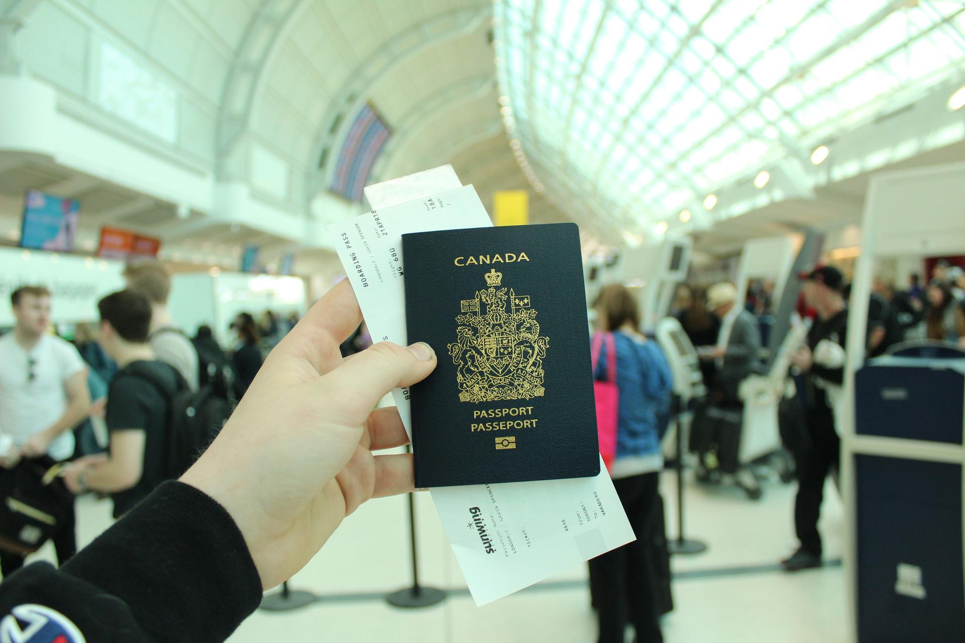 A person holds an open Canadian passport, symbolising citizenship documents under government review.