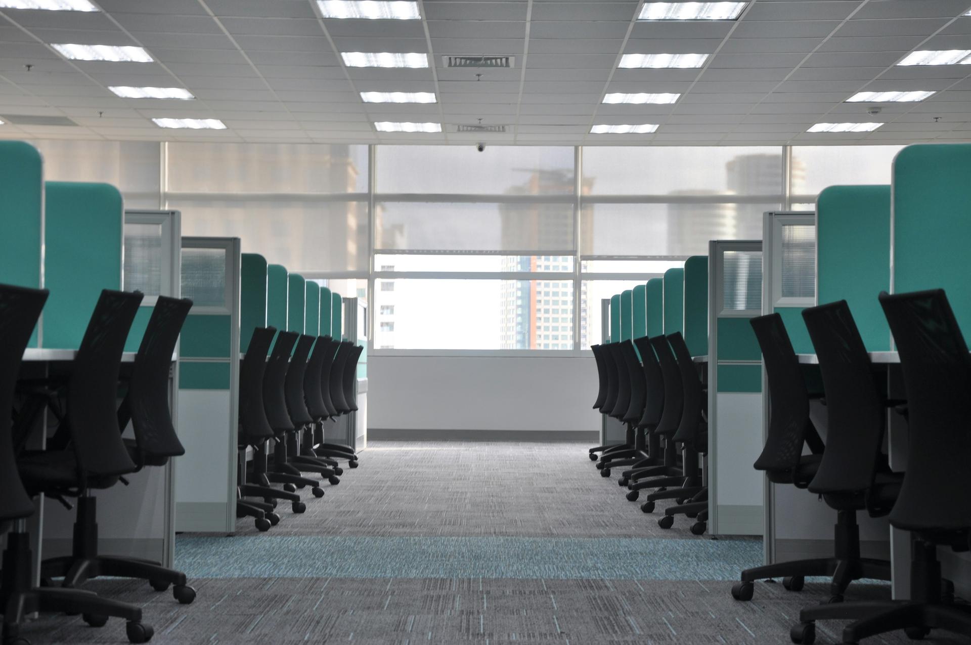 Rows of empty black office chairs and abandoned cubicles after layoffs at a US tech workplace.
