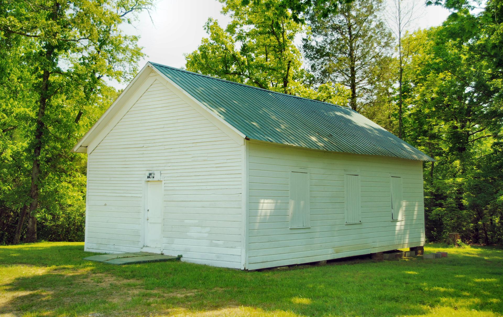A white Presbyterian church building among trees, representing diaspora congregations putting down roots in America.