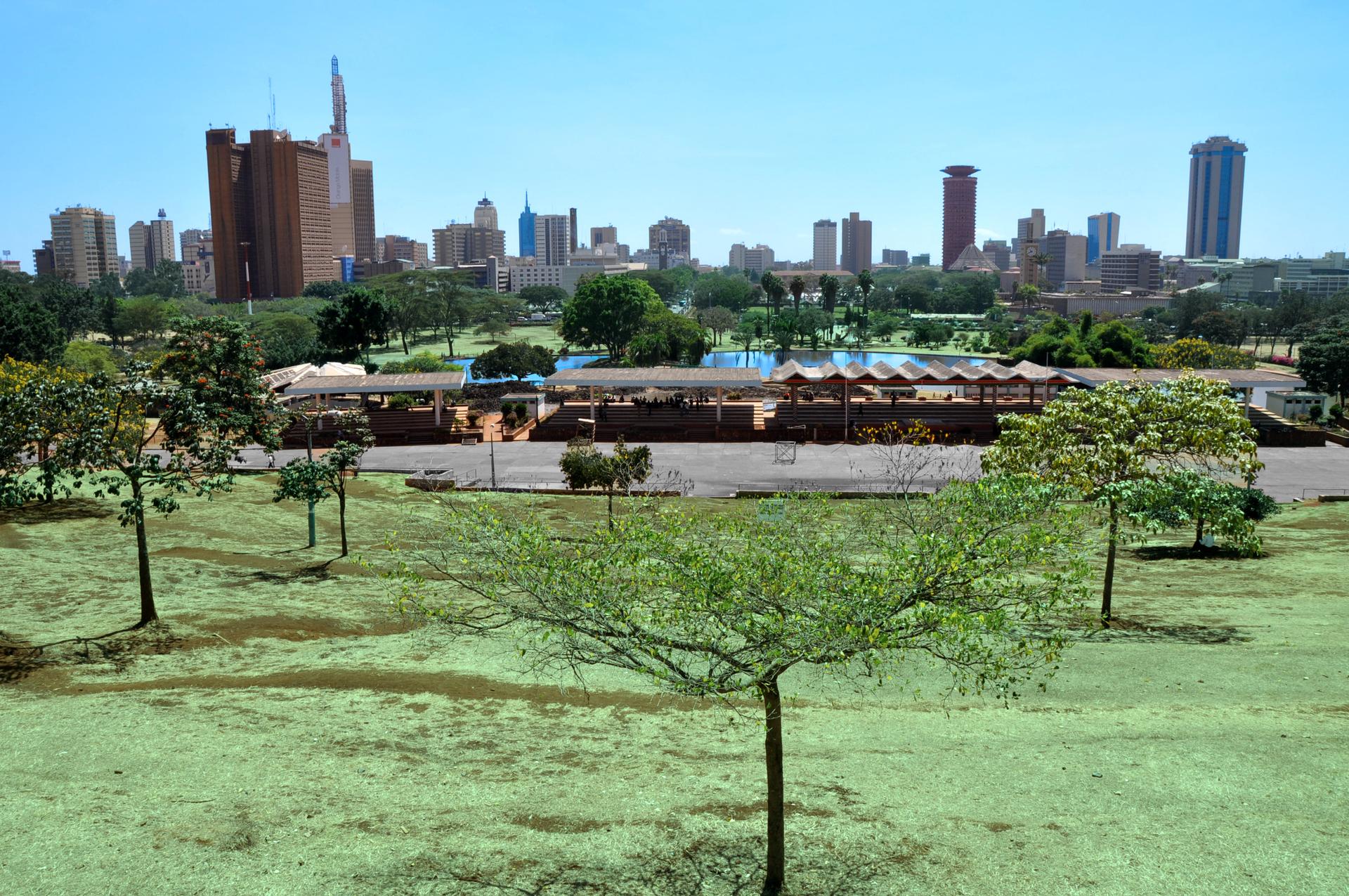 Nairobi's central business district skyline seen from Uhuru Park, with high-rise office towers under a bright sky.