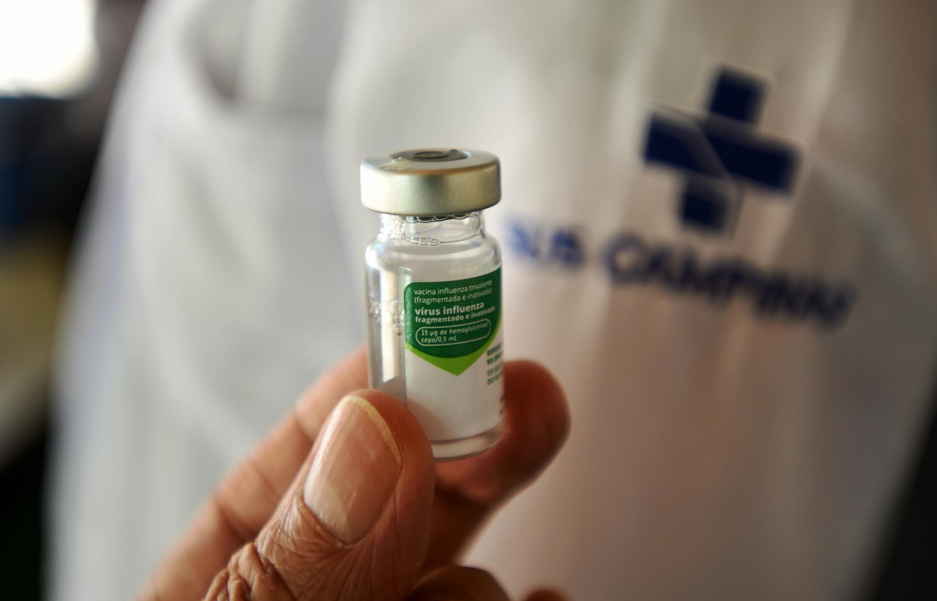 A vial of influenza vaccine with a syringe on a clinical surface, illustrating pandemic vaccine preparedness