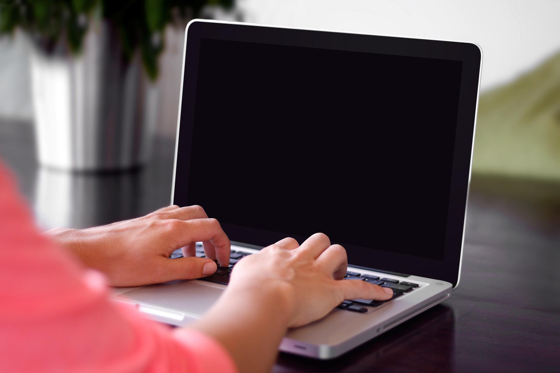 A person's hands typing on a laptop keyboard, illustrating online access to digital government services.