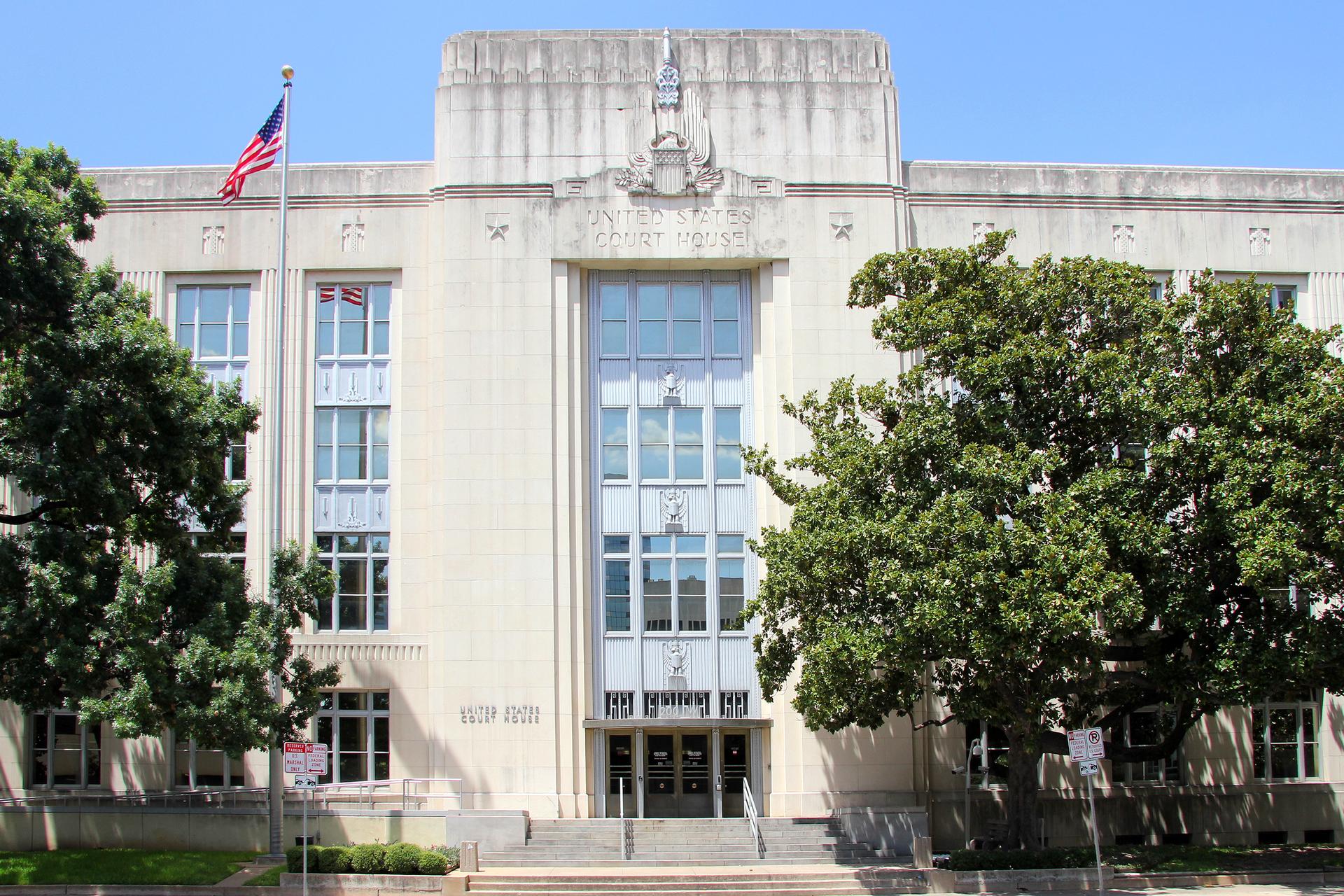 Exterior of a United States federal courthouse with stone columns under a clear sky.