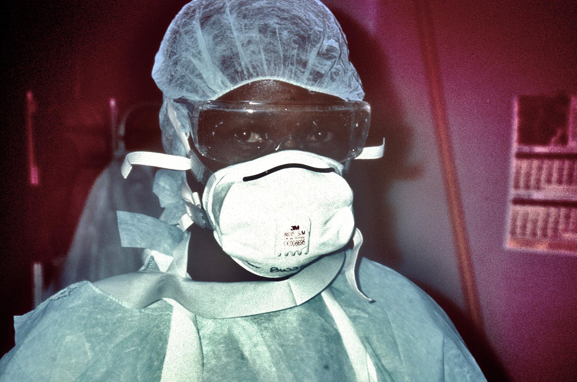 A nurse in full personal protective equipment during an Ebola outbreak response, gloved and gowned in an isolation setting