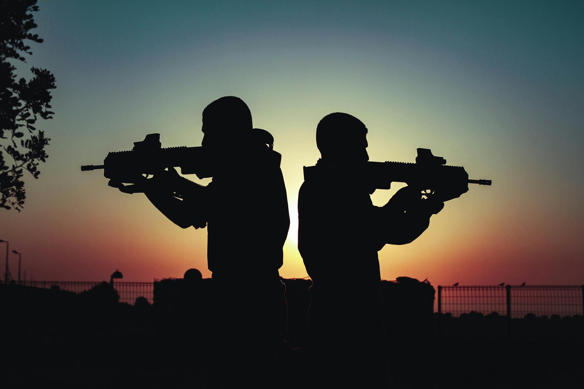 Silhouette of two soldiers carrying rifles against a dramatic sunset sky, evoking the front-line conditions described by Kenyan returnees from the Russia-Ukraine war.