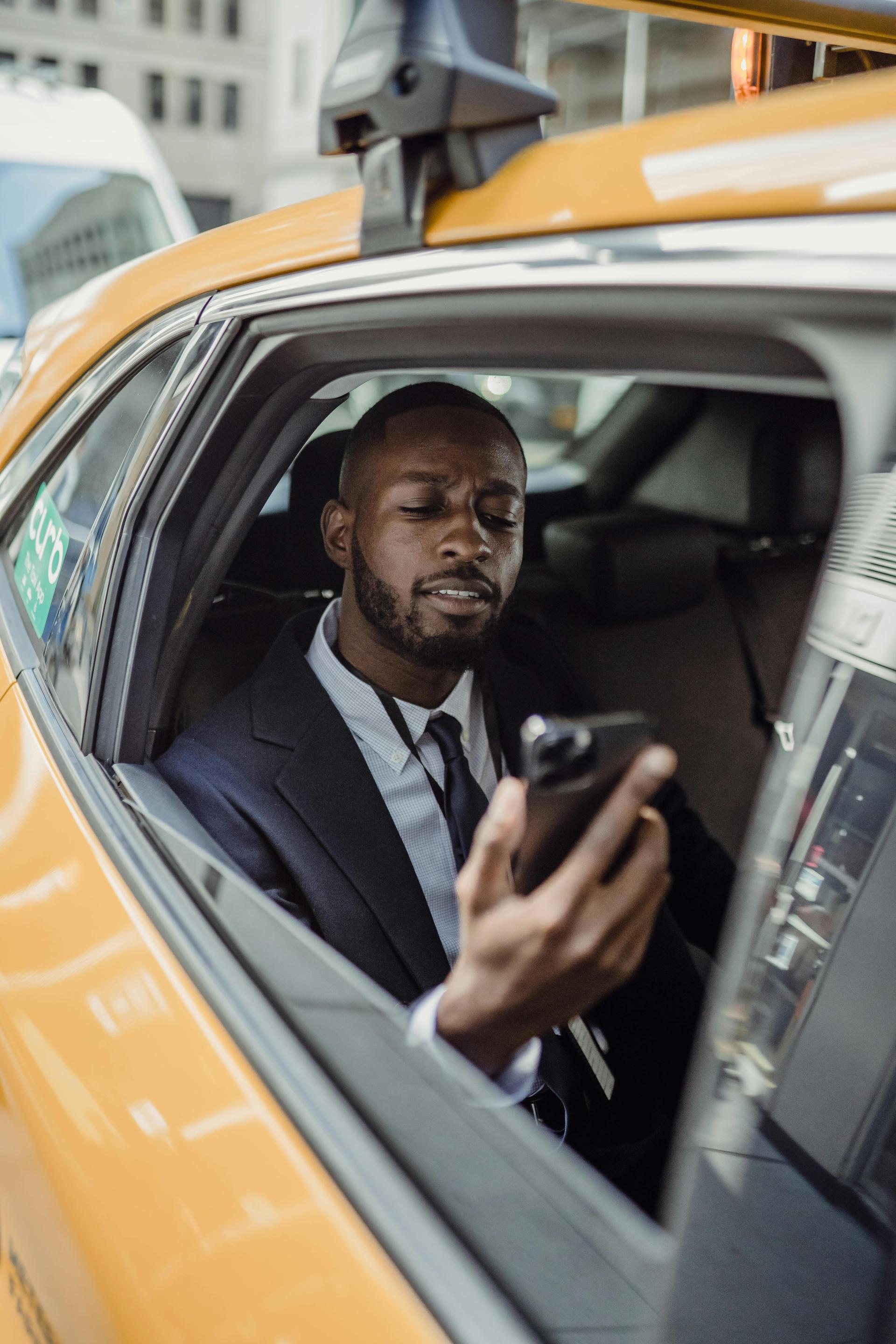A passenger in a taxi looks at a smartphone screen displaying a ride-hailing app in an urban setting.