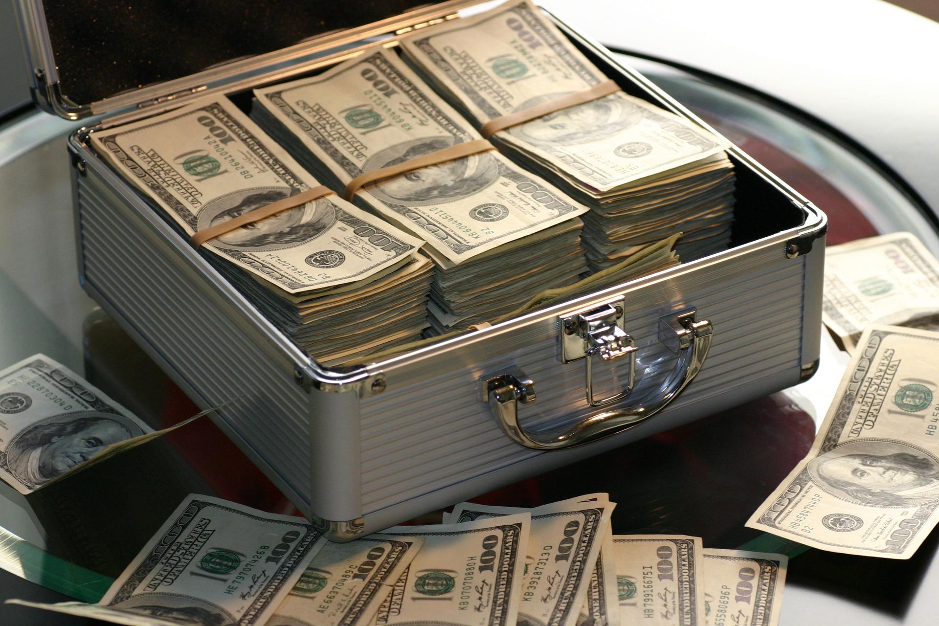 Bundles of US dollar banknotes packed inside an open briefcase, evoking cross-border remittance flows.