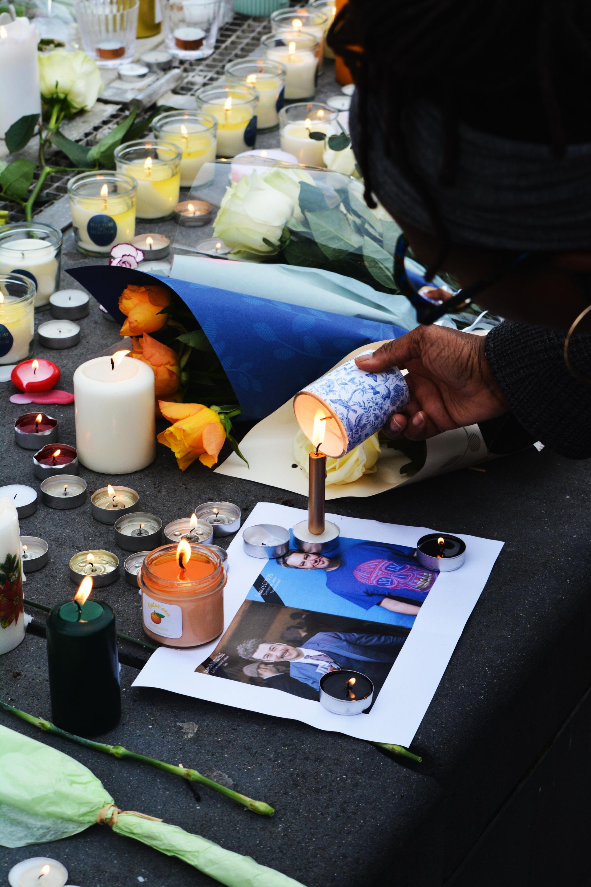 Lit memorial candles and flowers arranged at an evening vigil ceremony honouring a life lost