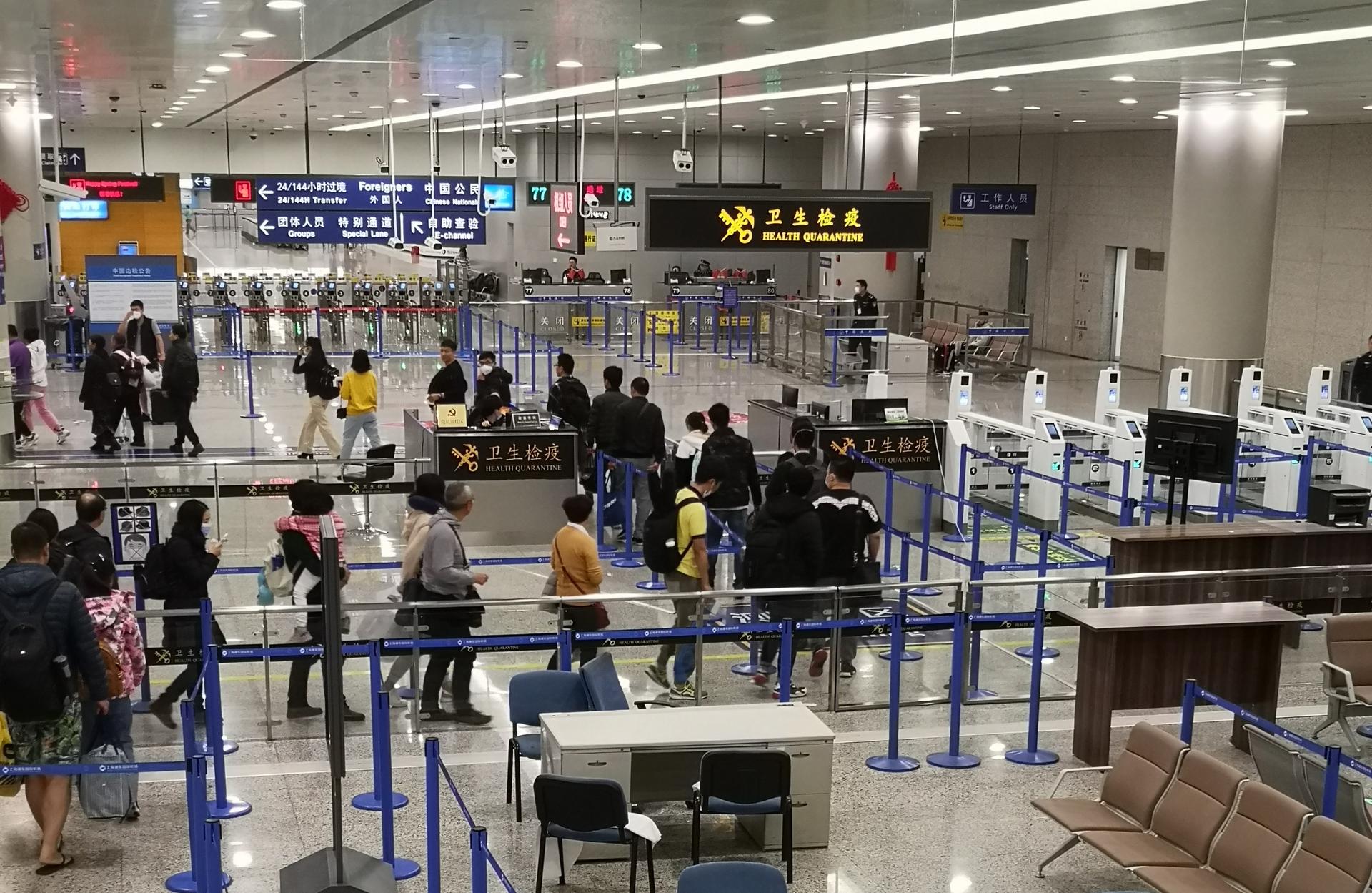 Health workers in protective gear screen arriving passengers' temperatures at an international airport during a disease outbreak