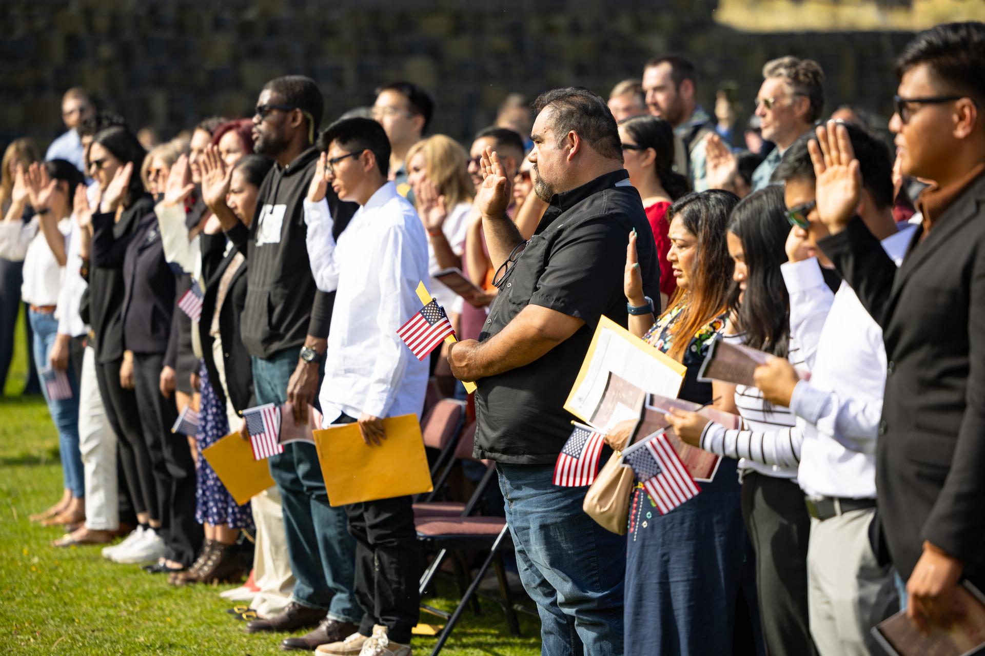 New Americans raise their right hands to take the oath of citizenship at a US naturalisation ceremony