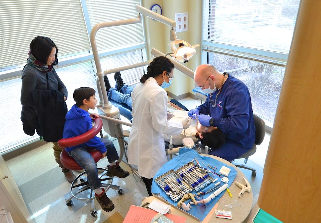 Dental students treat children at a free community clinic, illustrating widening gaps in access to routine dental care.
