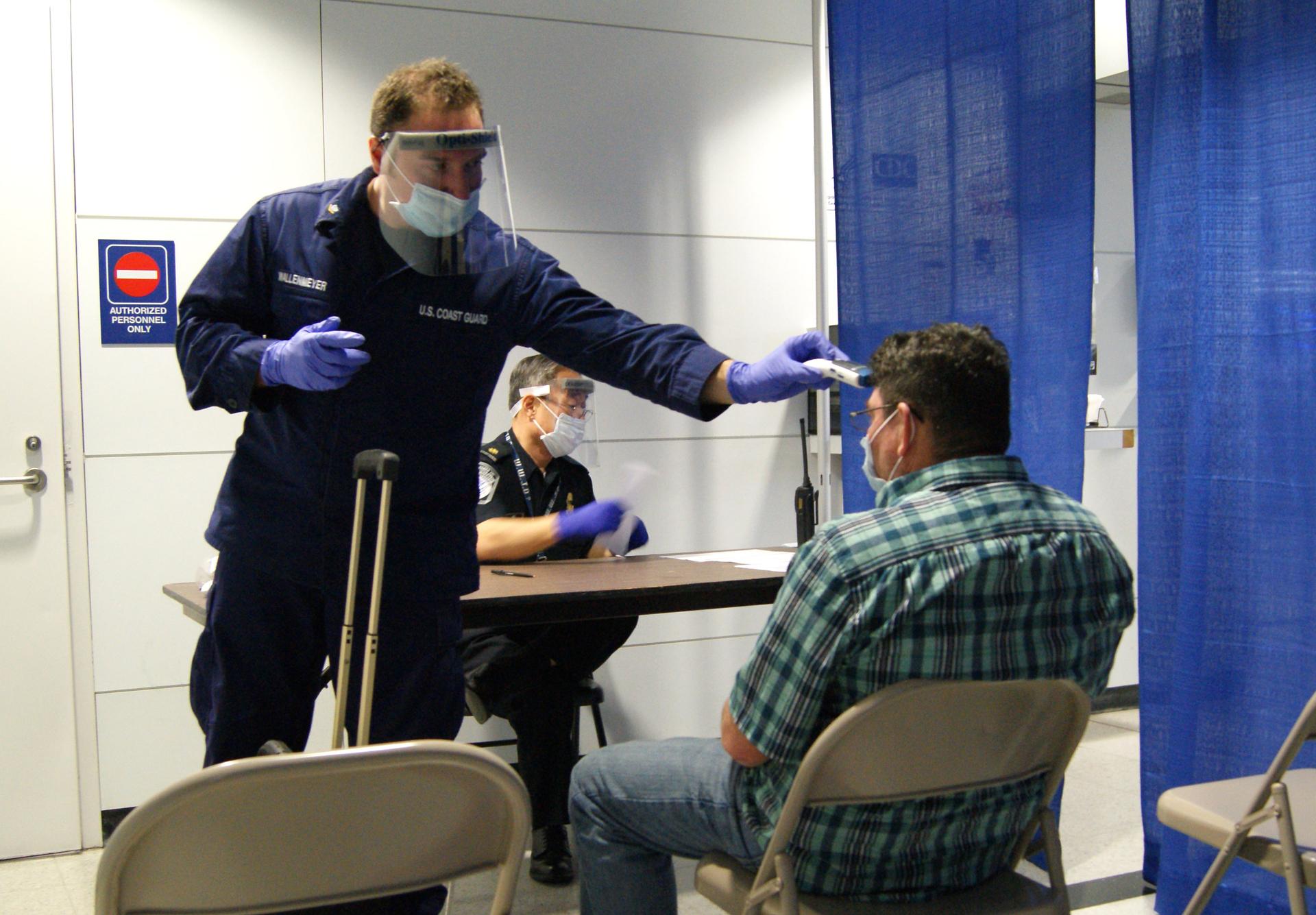 A health officer screens an arriving international air passenger for Ebola symptoms at an airport checkpoint.
