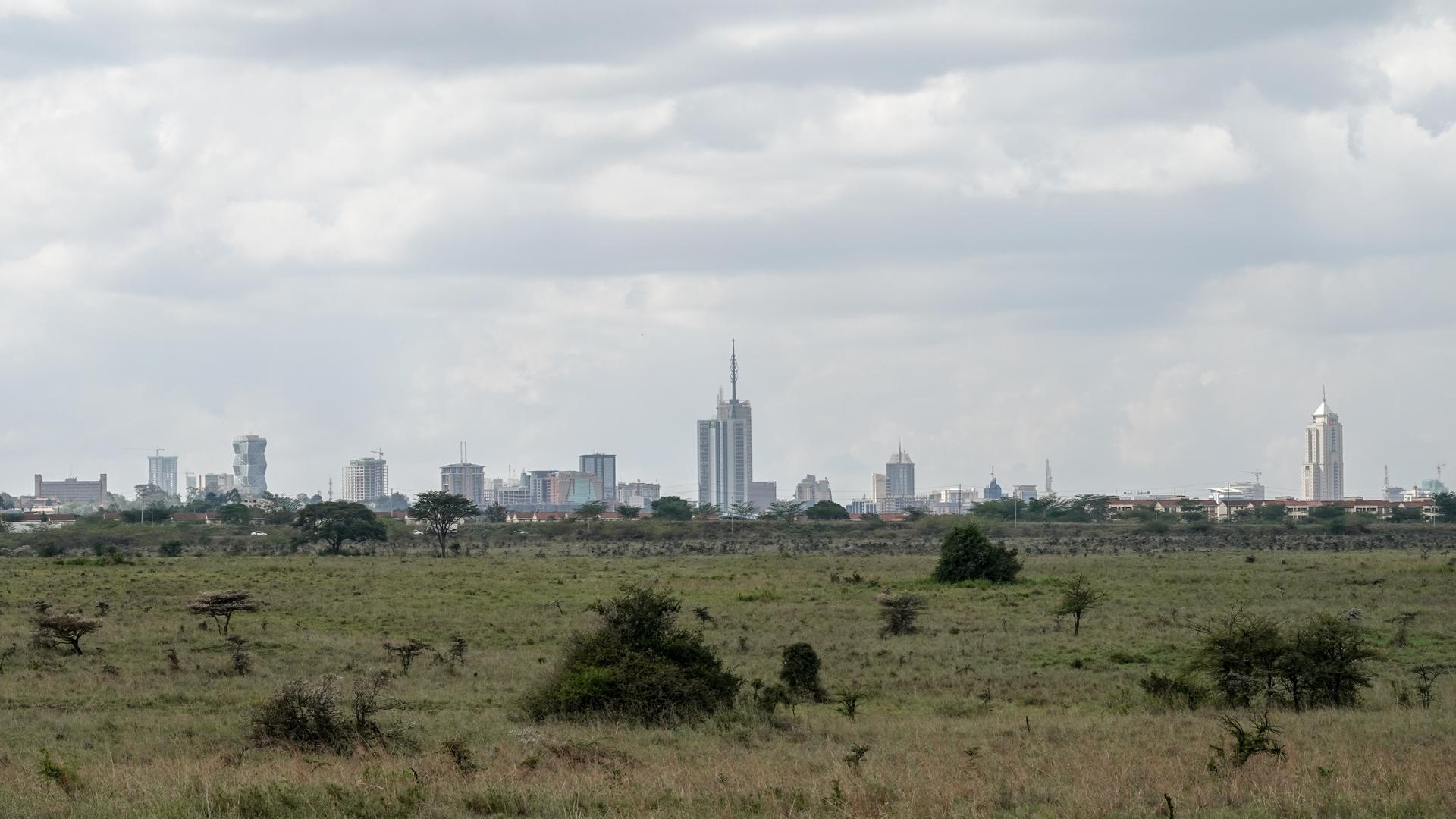 Nairobi's downtown skyline rising behind open savannah grassland, viewed from the edge of Nairobi National Park, Kenya.