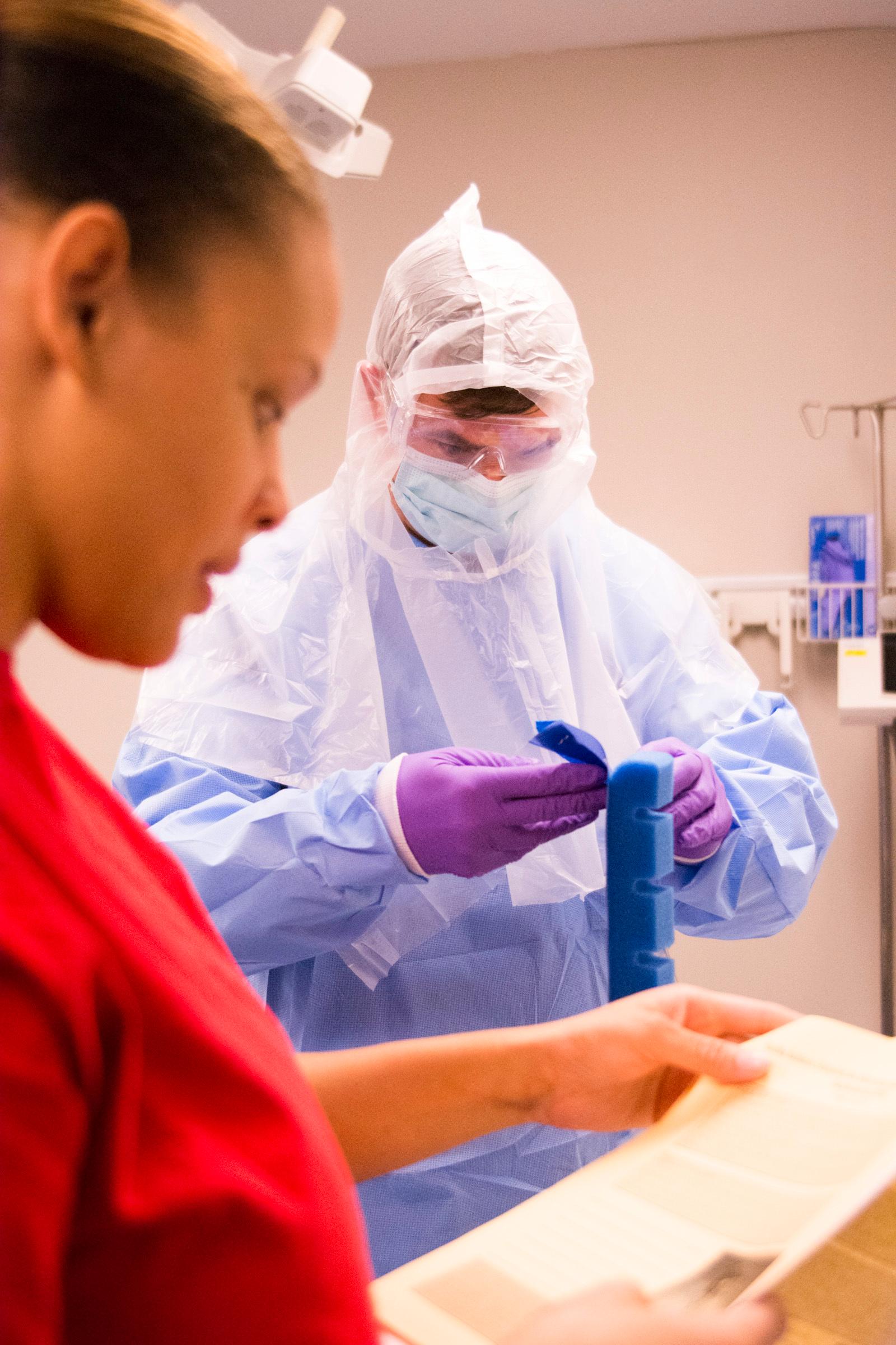 U.S. Army medical staff practice putting on simulated Ebola personal protective equipment during a military response training session.