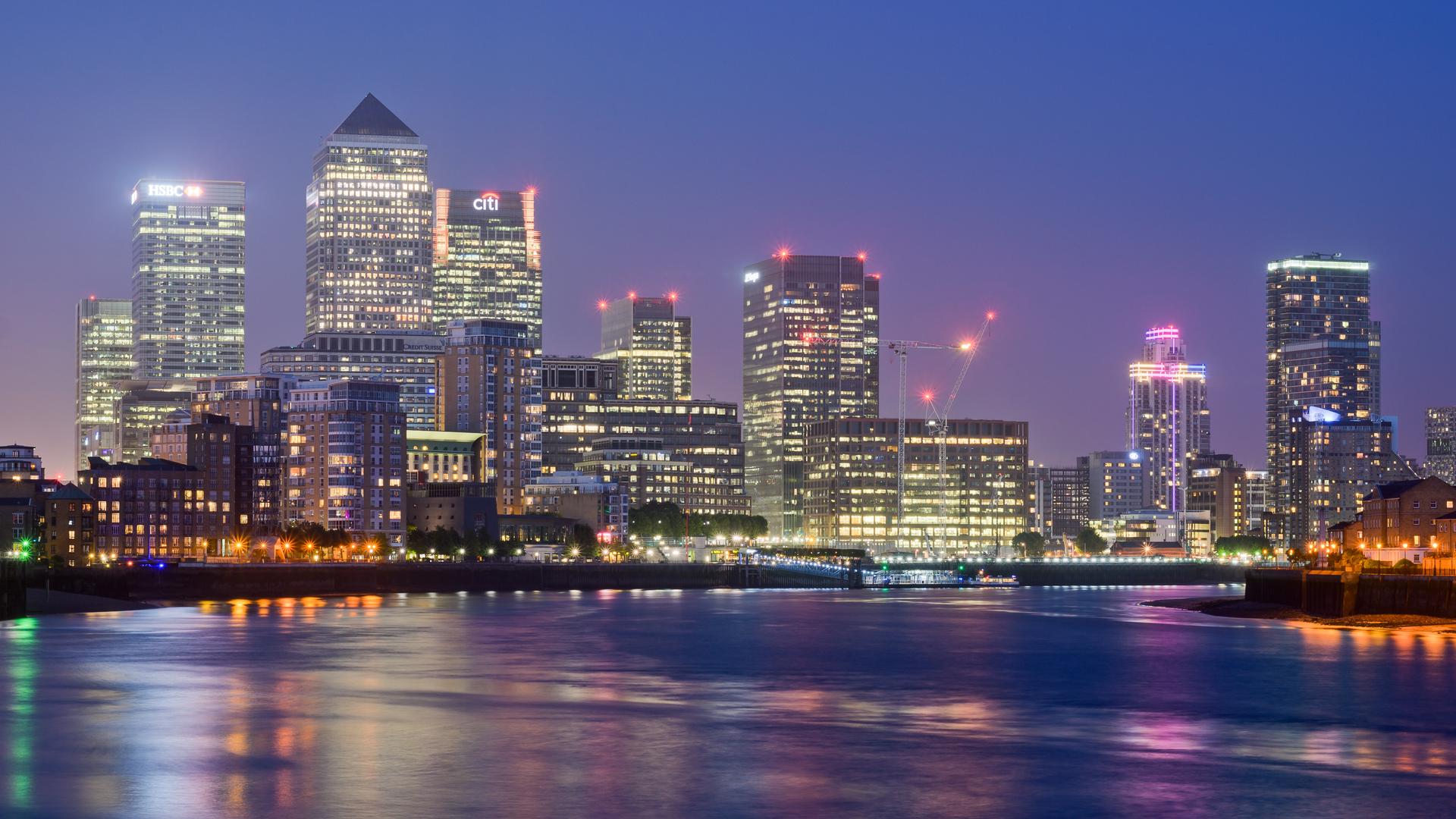 The towers of Canary Wharf, London's financial and technology district, seen across the water at dusk.