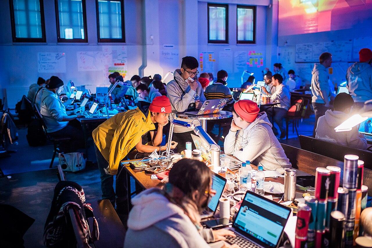 Young technologists work together at laptops during a hackathon, the kind of collaborative coding session central to diaspora tech events.