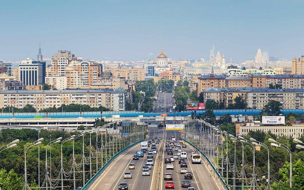 A wide Moscow avenue with apartment blocks and traffic under an overcast Russian sky