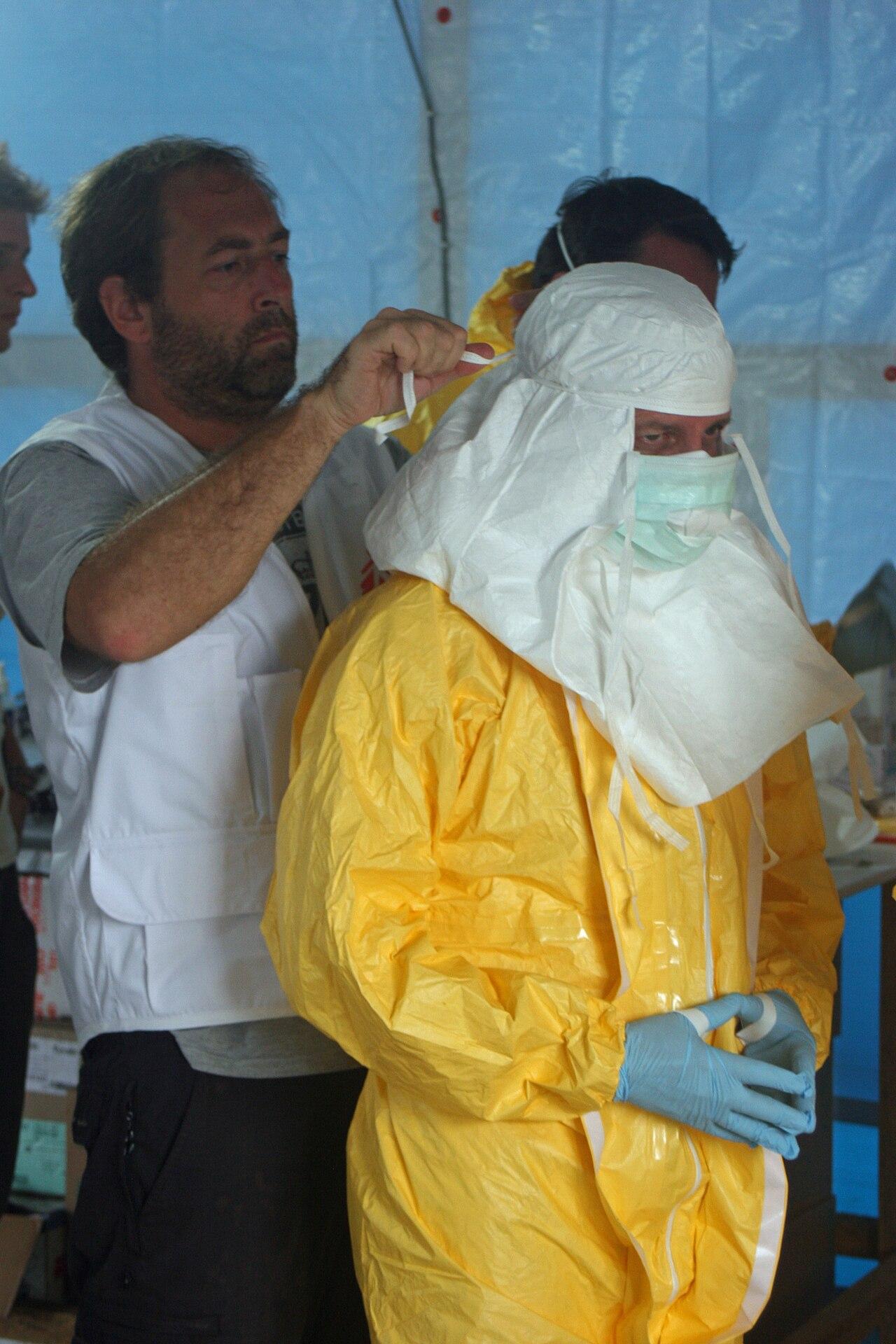 Health workers in protective equipment prepare to enter an Ebola treatment unit during an outbreak response.