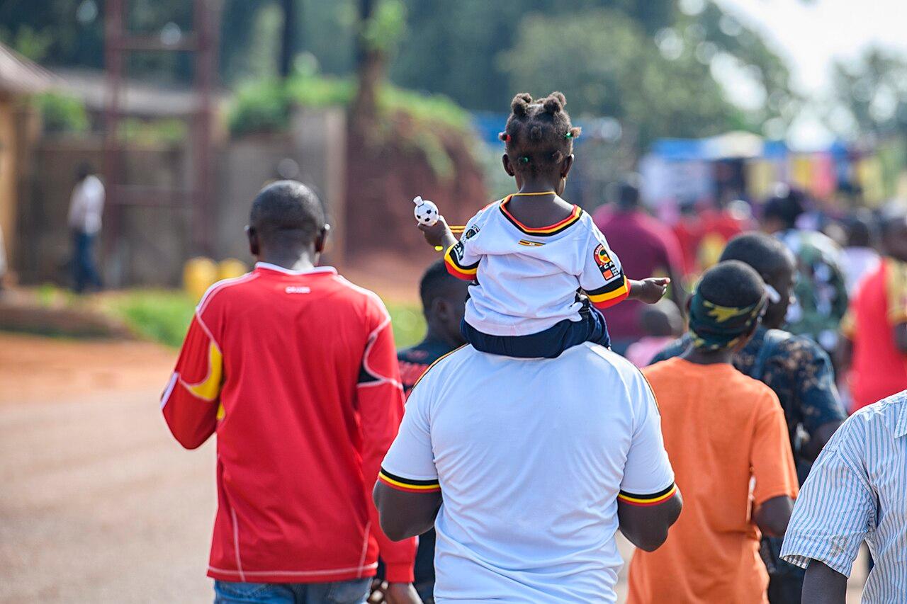 A young African football fan in national-team colours cheering from the stands at an international match