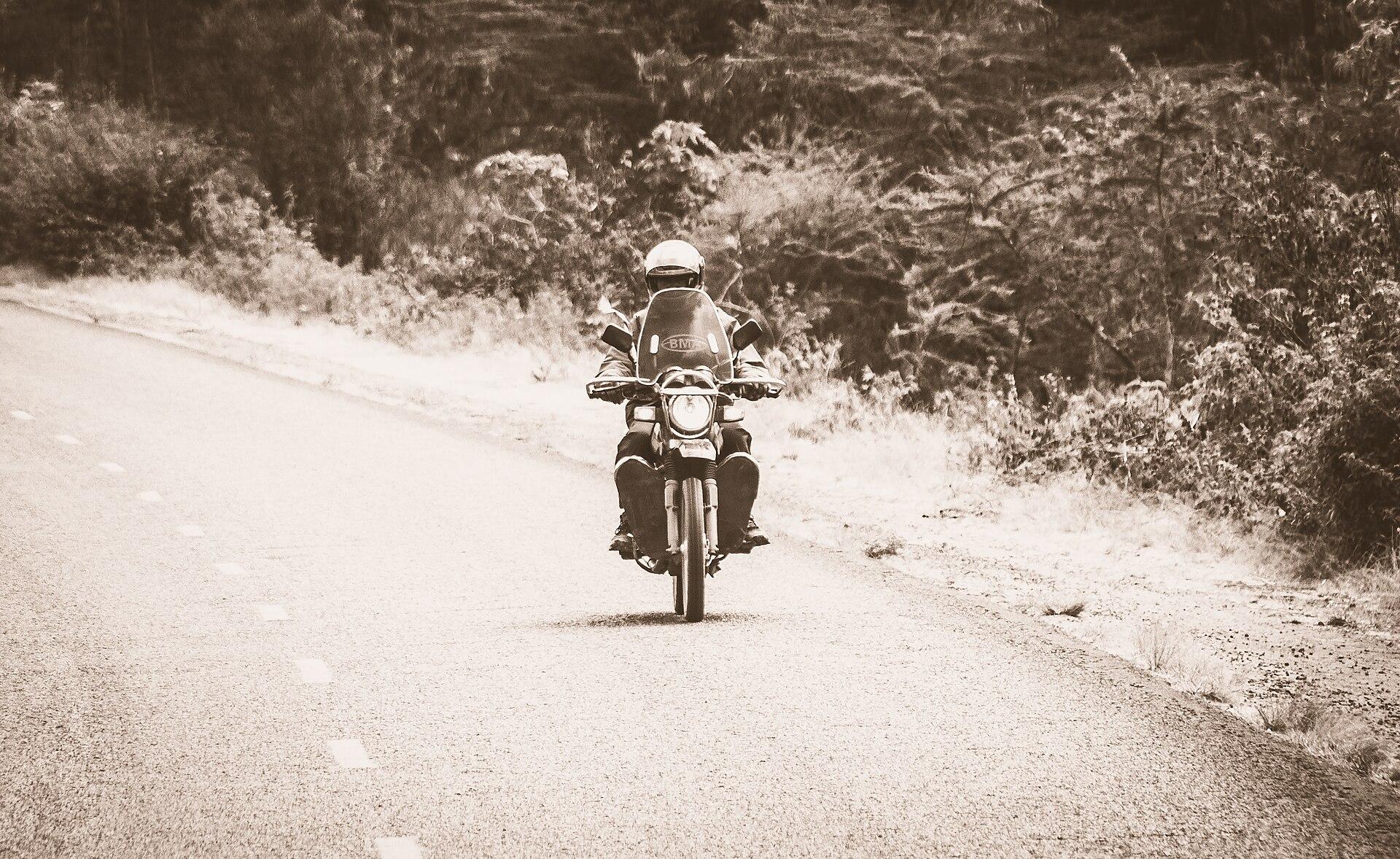A boda boda motorcycle-taxi rider waits with his motorcycle on a Kenyan street.