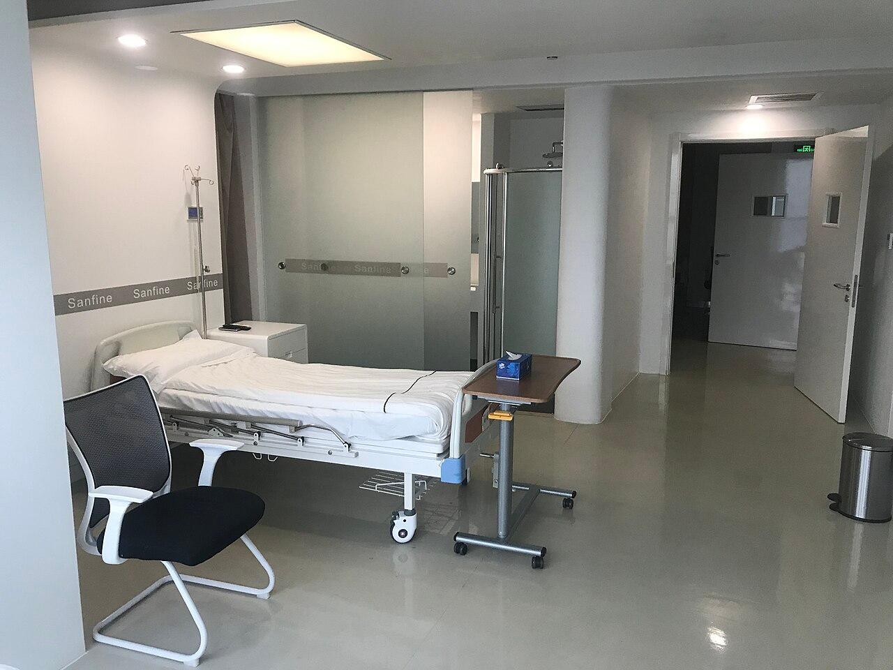 An empty modern hospital ward with neatly made beds, evoking a long-term care facility.