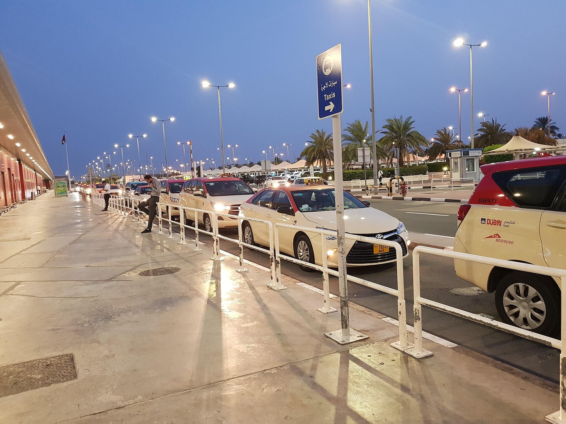 Travellers and vehicles outside a terminal at Dubai International Airport in the early morning, United Arab Emirates