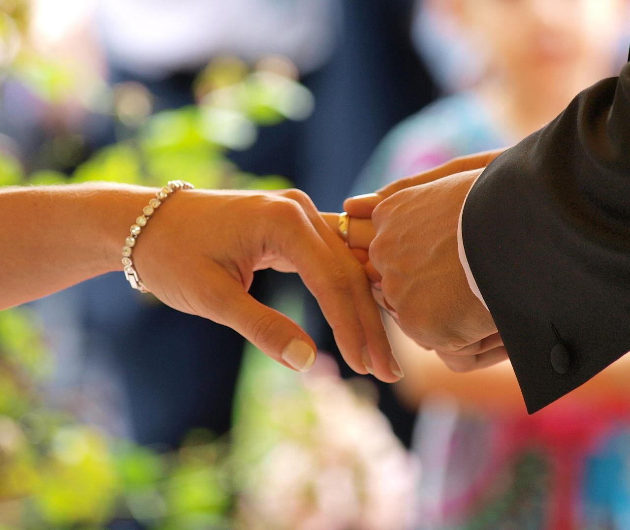 A wedding ring being placed on a partner's finger during a marriage ceremony