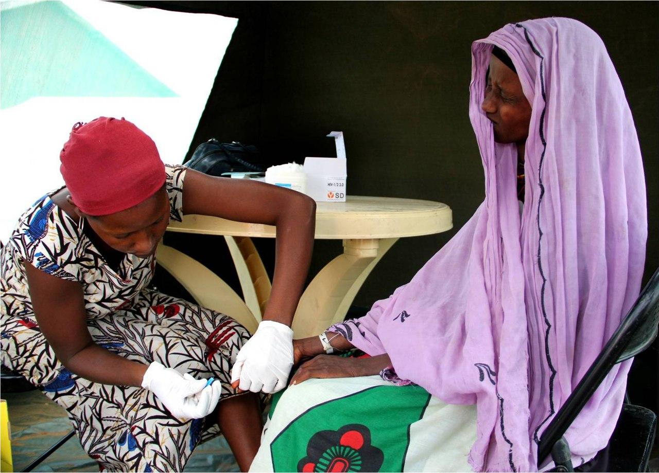 A health worker draws blood from a Kenyan woman's finger for an HIV test at a community clinic.