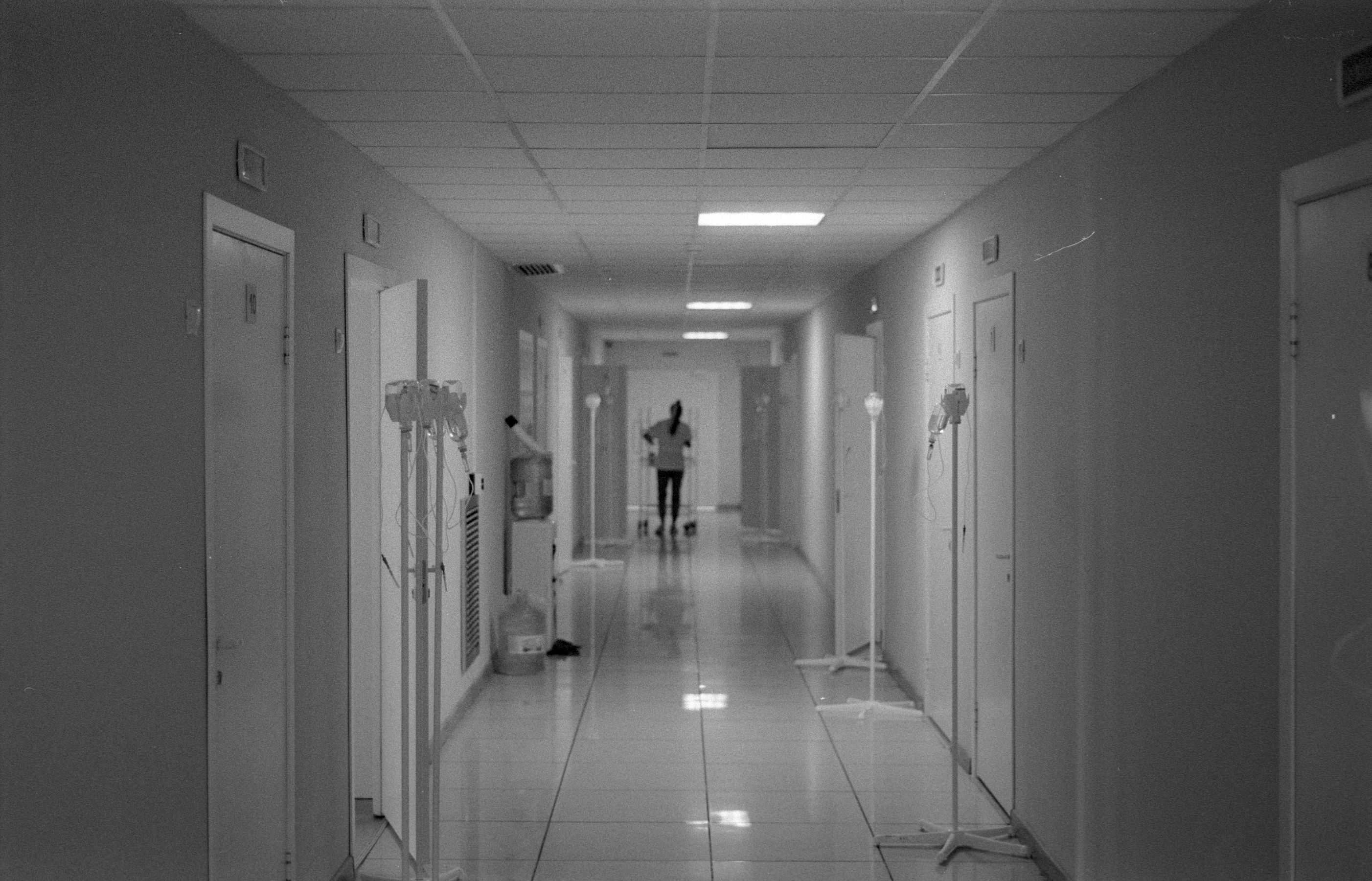A nurse stands alone at the end of a hospital corridor, evoking the long wait Kenyan nurses face for NHS placements.
