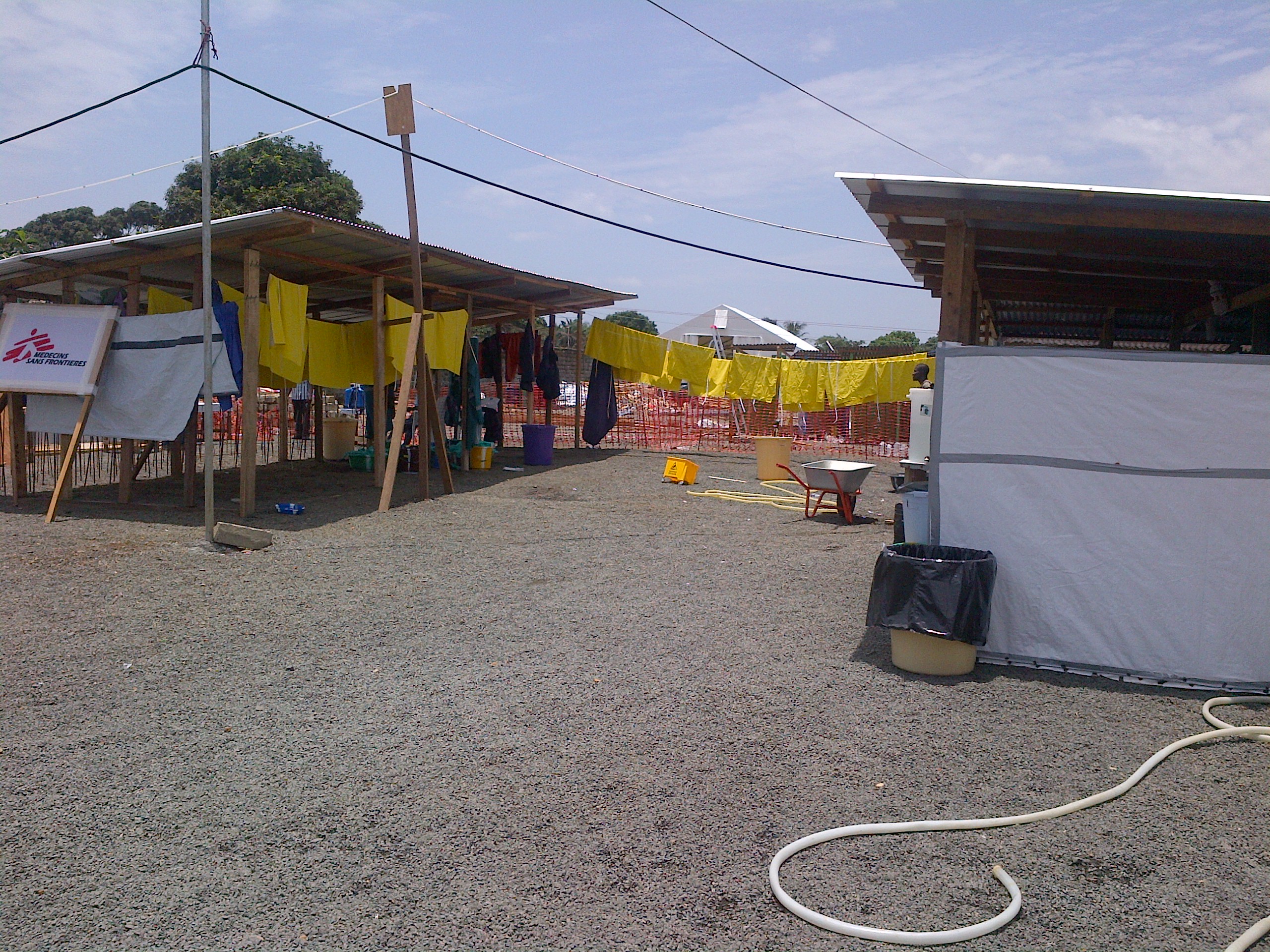 Health workers in protective suits stand outside an Ebola treatment unit during an outbreak response in Africa.