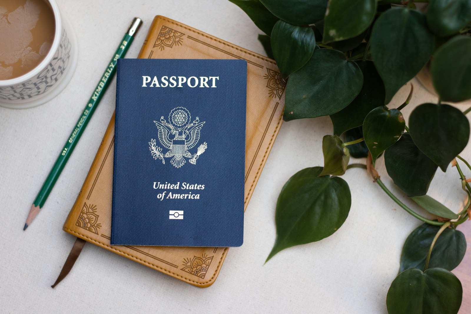 A US passport resting on a wooden table beside a cup of coffee, symbolising the new green card consular processing requirement