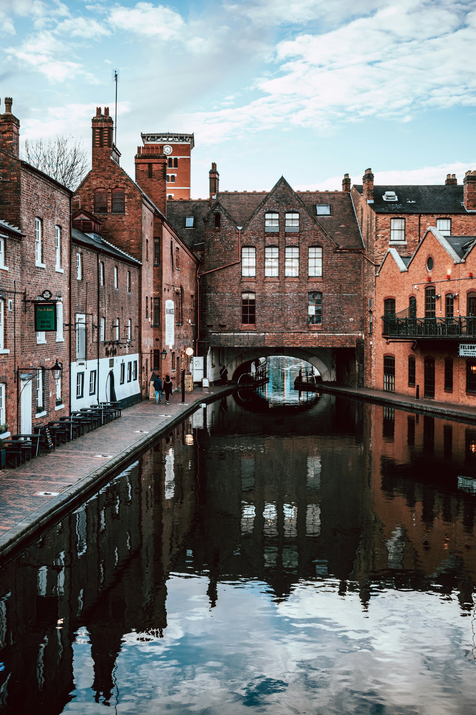 Brown brick buildings beside a river in Birmingham, England, on an overcast day, conveying an urban West Midlands streetscape.