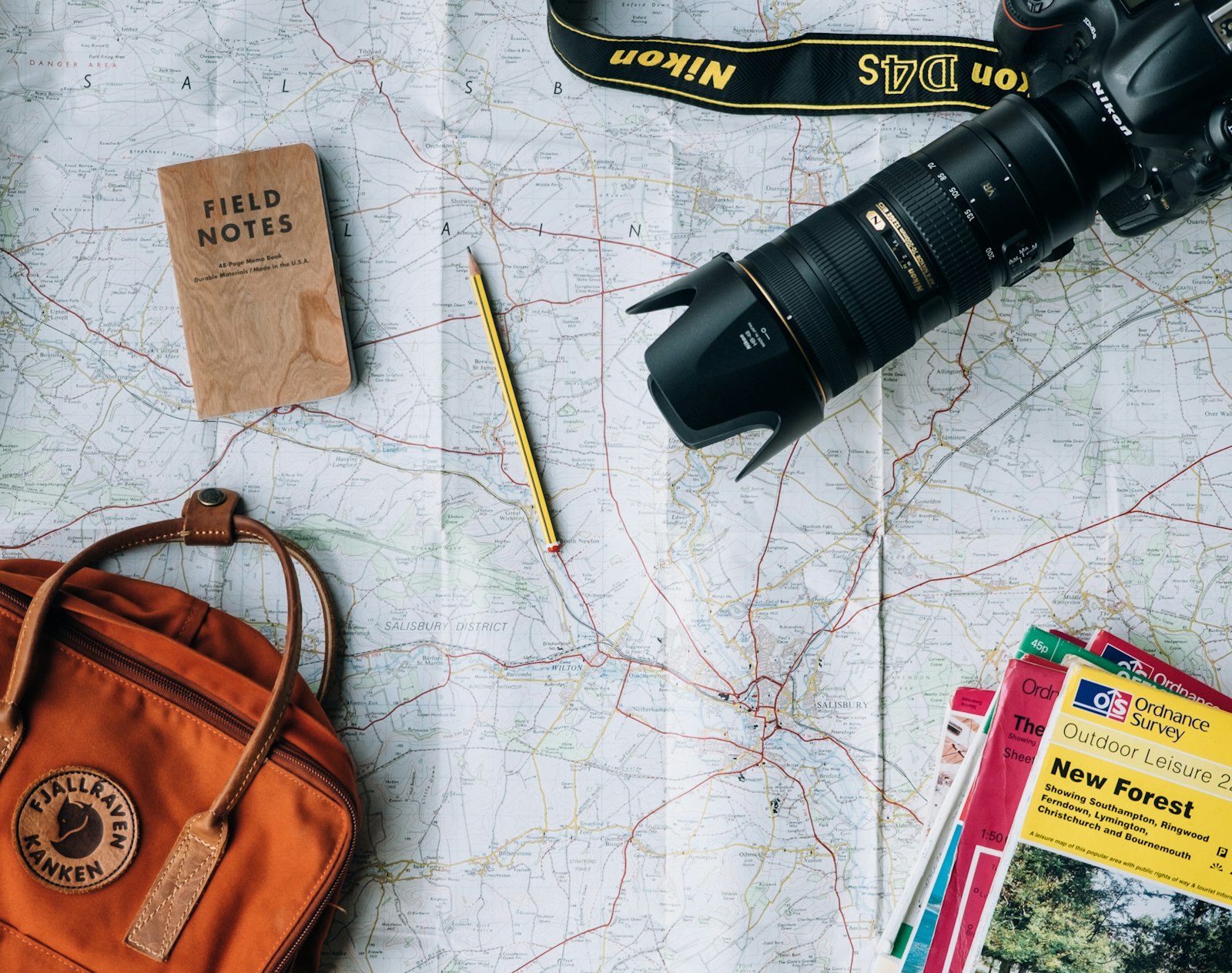 An open passport rests on a map next to a small notebook, suggesting international travel and consular processing for immigration applications.